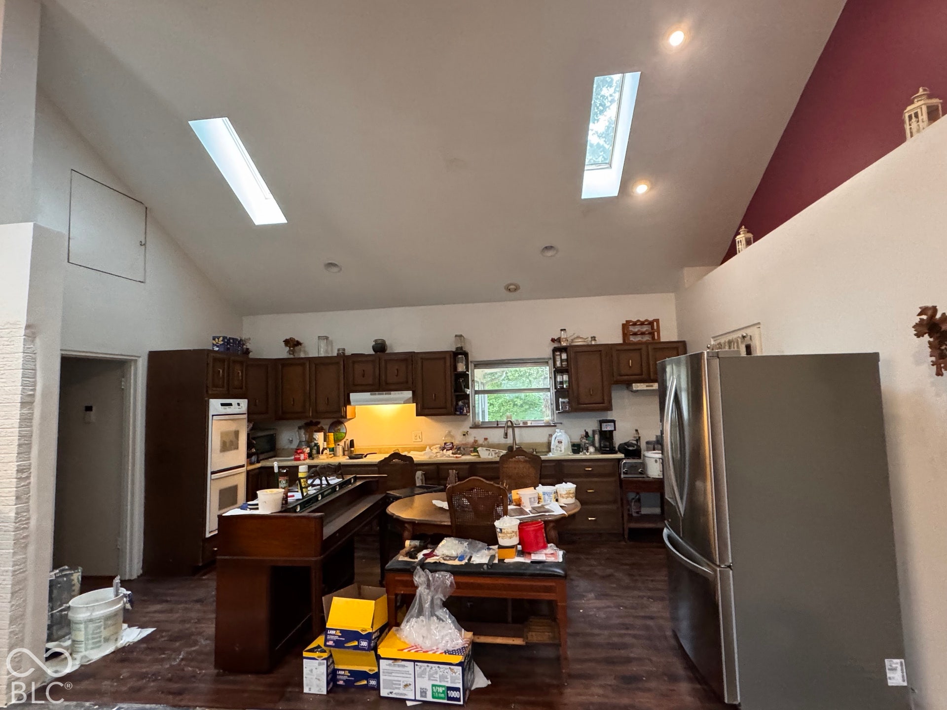 Vaulted ceiling featuring two skylights, recessed lighting, wood-finish flooring, and cabinetry