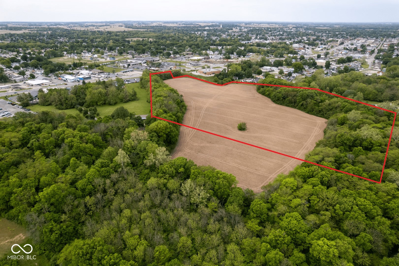 Expansive land parcel featuring clear acreage, perimeter tree lines, and proximity to developed areas