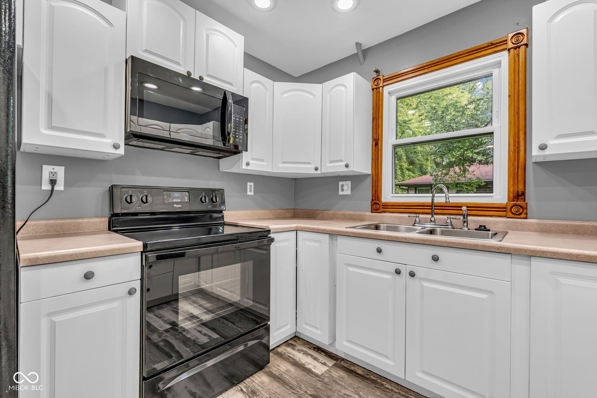White cabinetry with dark hardware, built-in black microwave, and black electric range