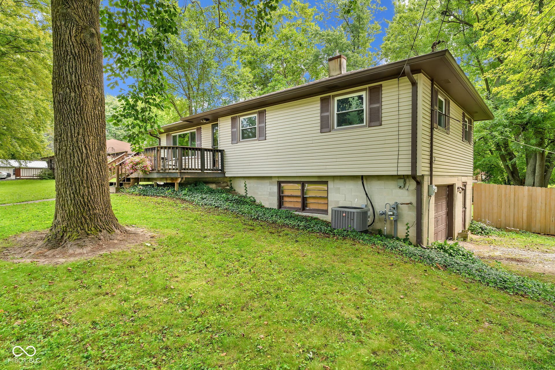 Exterior featuring tan horizontal siding, brown shutters, a wood deck with railings, and a walk-out basement