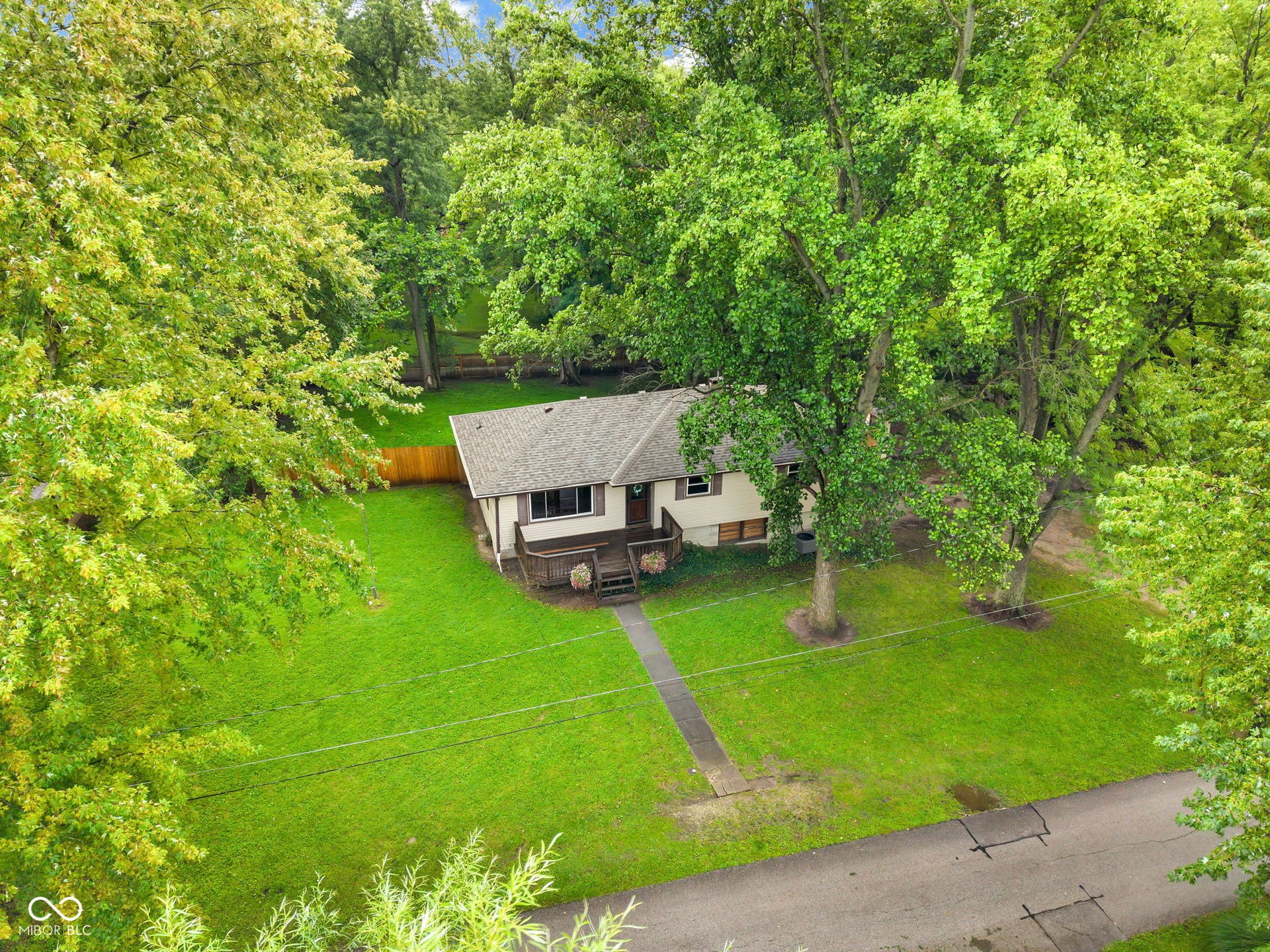 Single-story residence with a pitched roof, front-facing deck, and mature trees