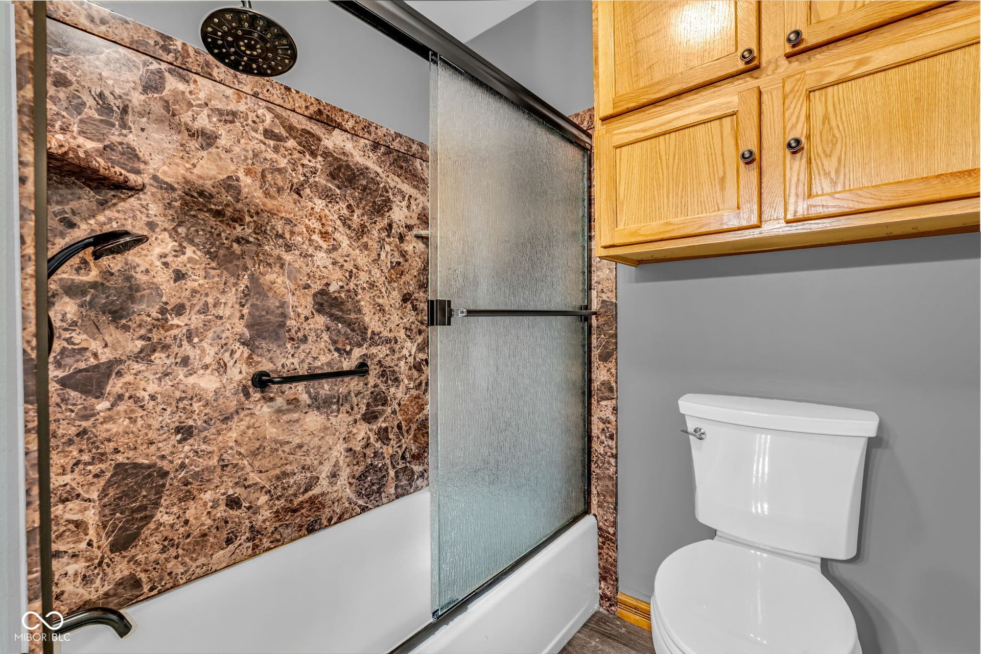 Tub/shower combination with a patterned surround, rain shower head, hand-held shower, and sliding glass enclosure