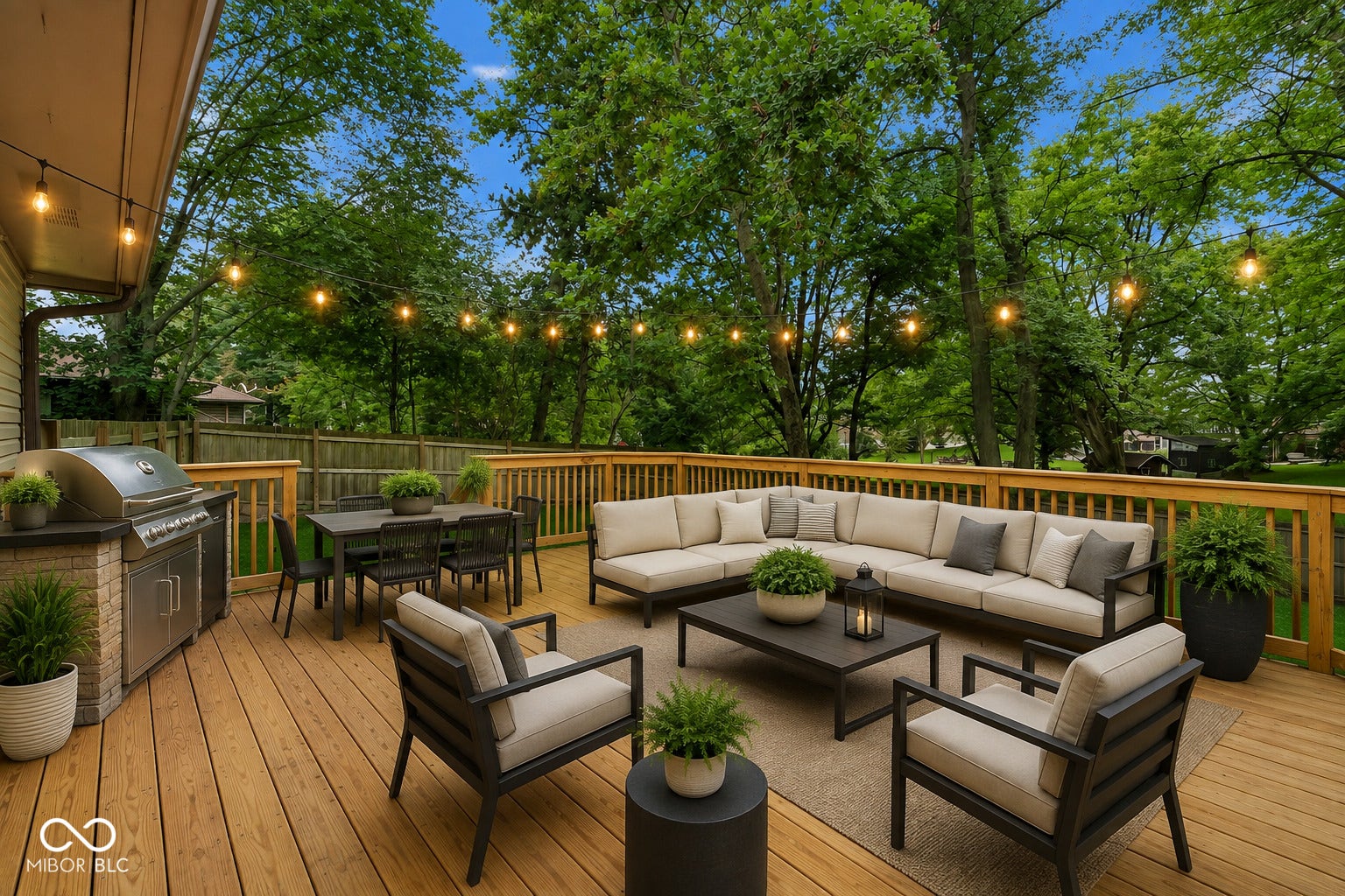 Virtually Altered - Spacious wood deck featuring a built-in grill station with stone-finish base, ample space for outdoor dining, and string lighting