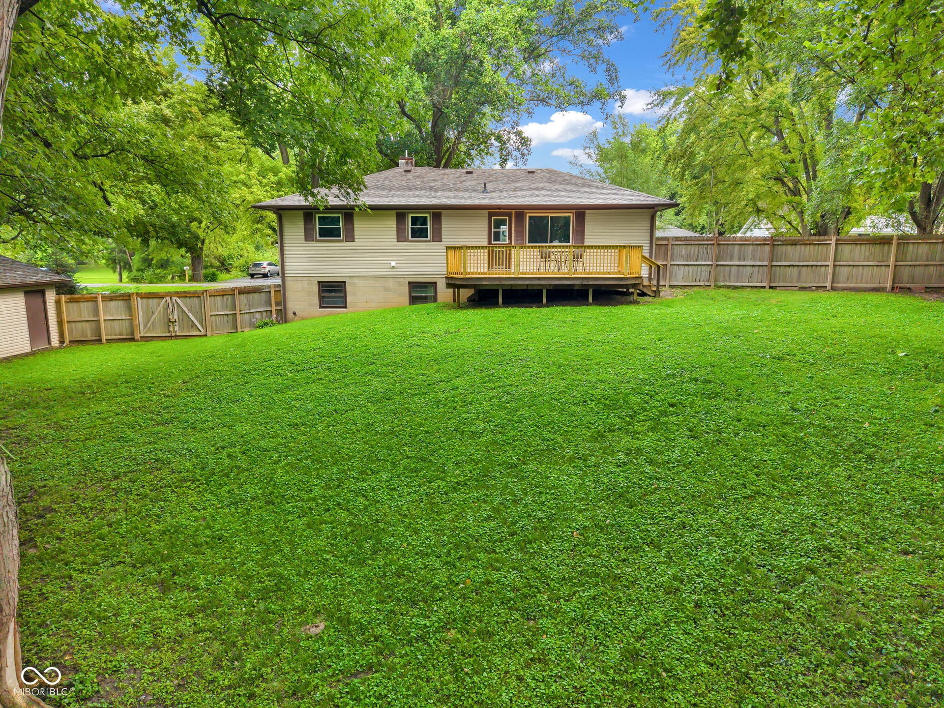 Expansive lawn with a wood privacy fence, leading to a wood deck with a built-in railing