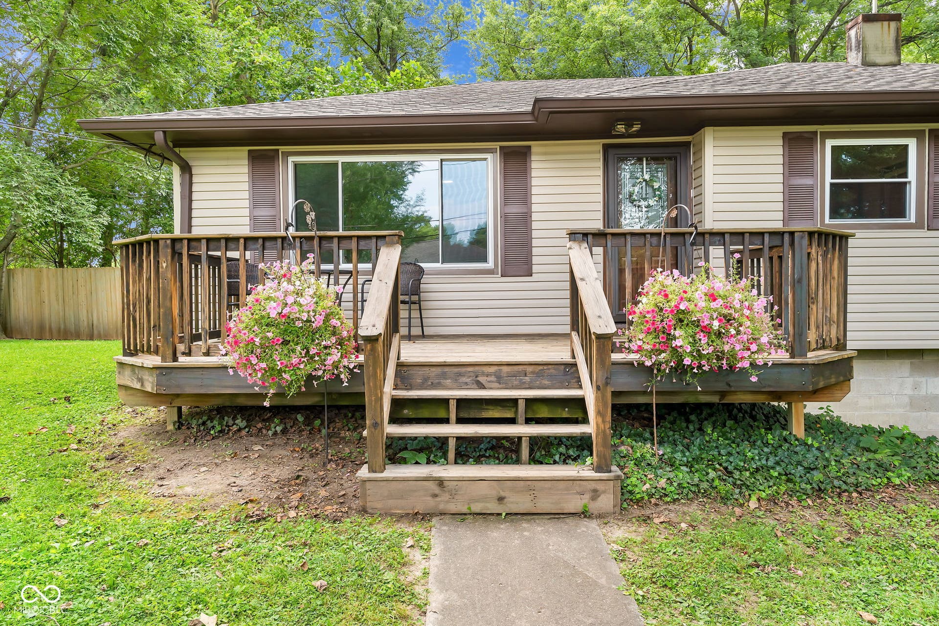 Property exterior featuring light-colored siding, dark brown shutters, and a front entry deck with wood railings