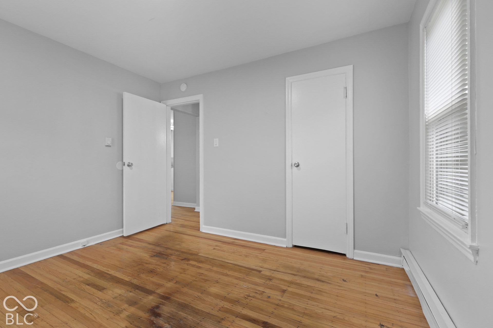 Room featuring wood-finish flooring, neutral wall paint, and white paneled doors