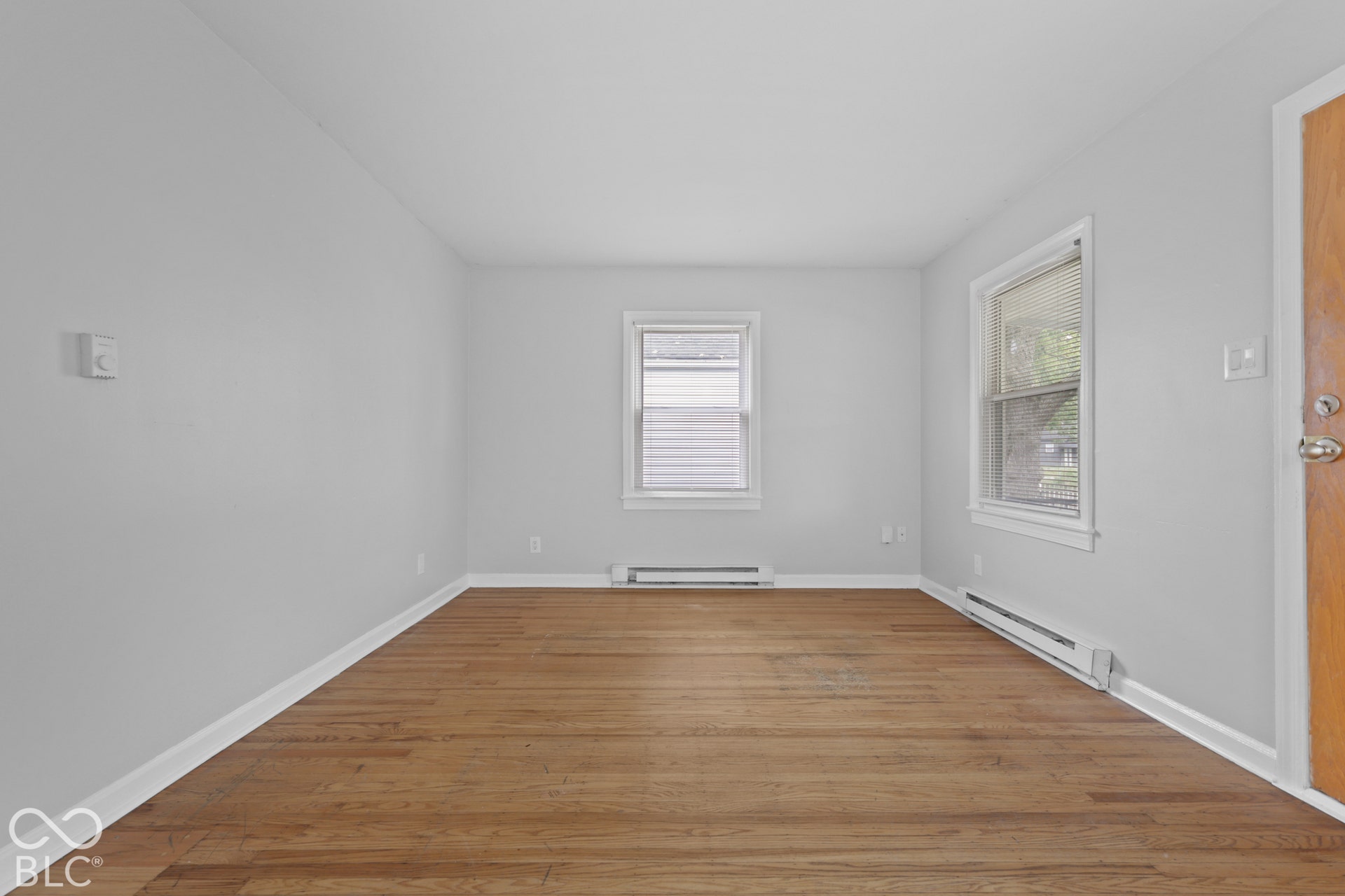 Room featuring wood-finish flooring, neutral wall paint, and two double-hung windows