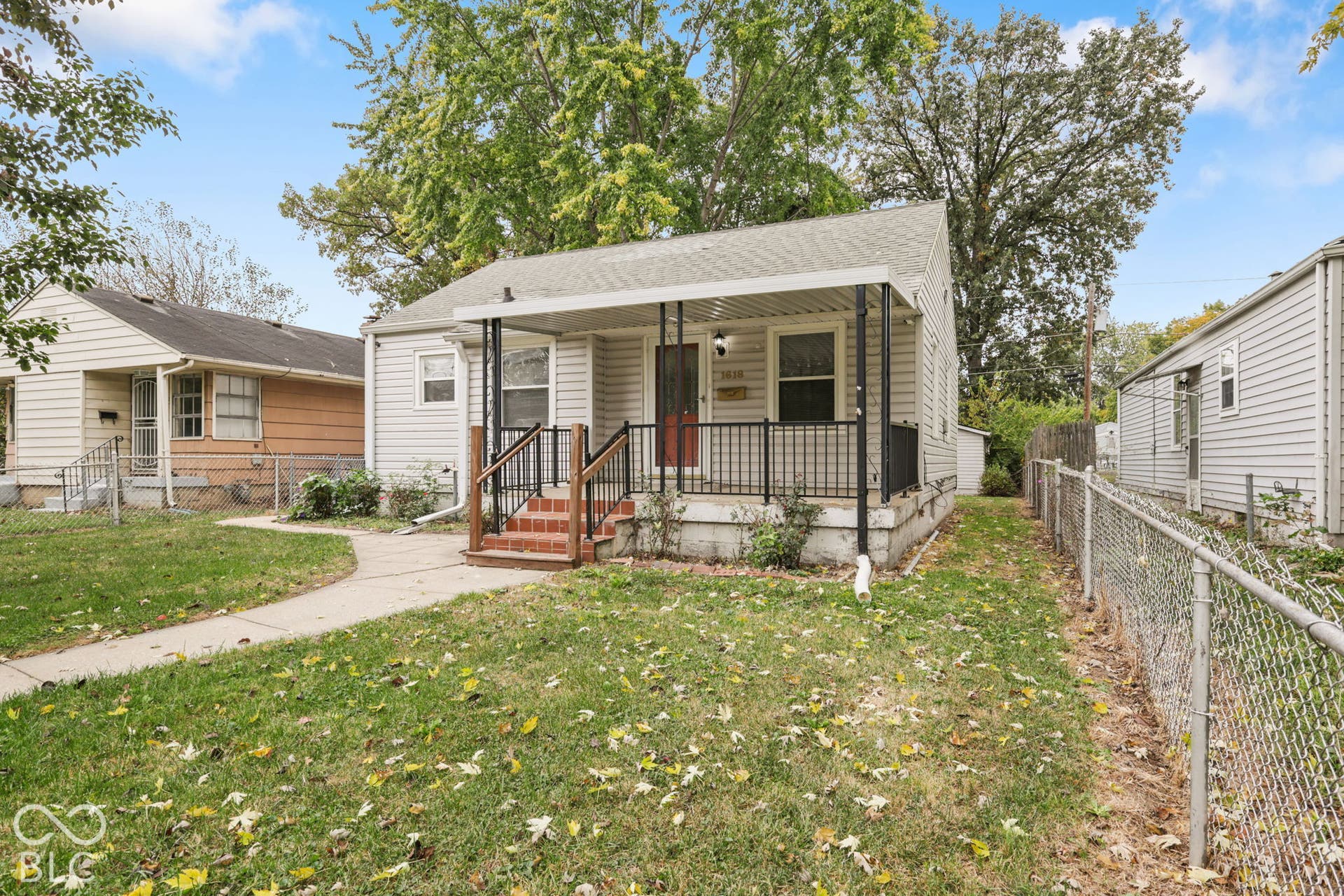 Exterior featuring gray horizontal siding, a covered front porch with metal railing, and brick front steps