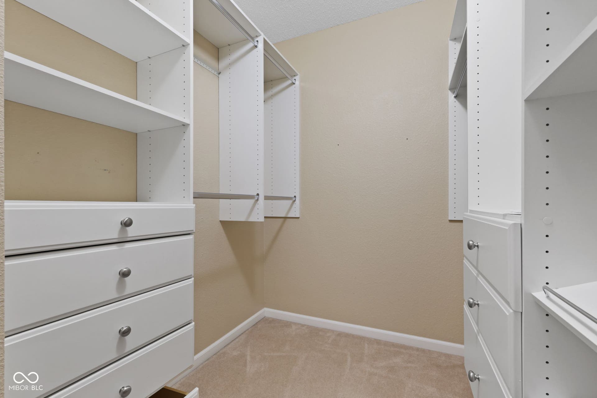 Spacious walk-in closet featuring built-in organizers for convenient storage.