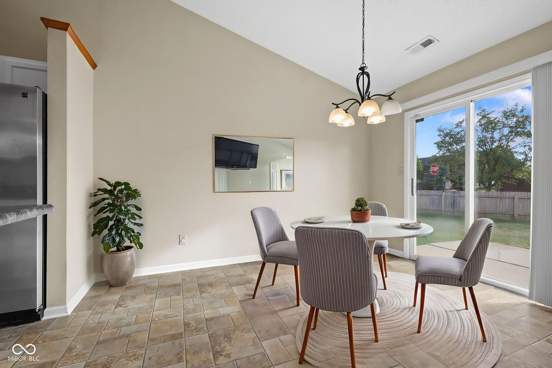 Virtually Altered - Virtually staged dining area highlighting the open layout and direct views of the back porch and large, fully fenced backyard.