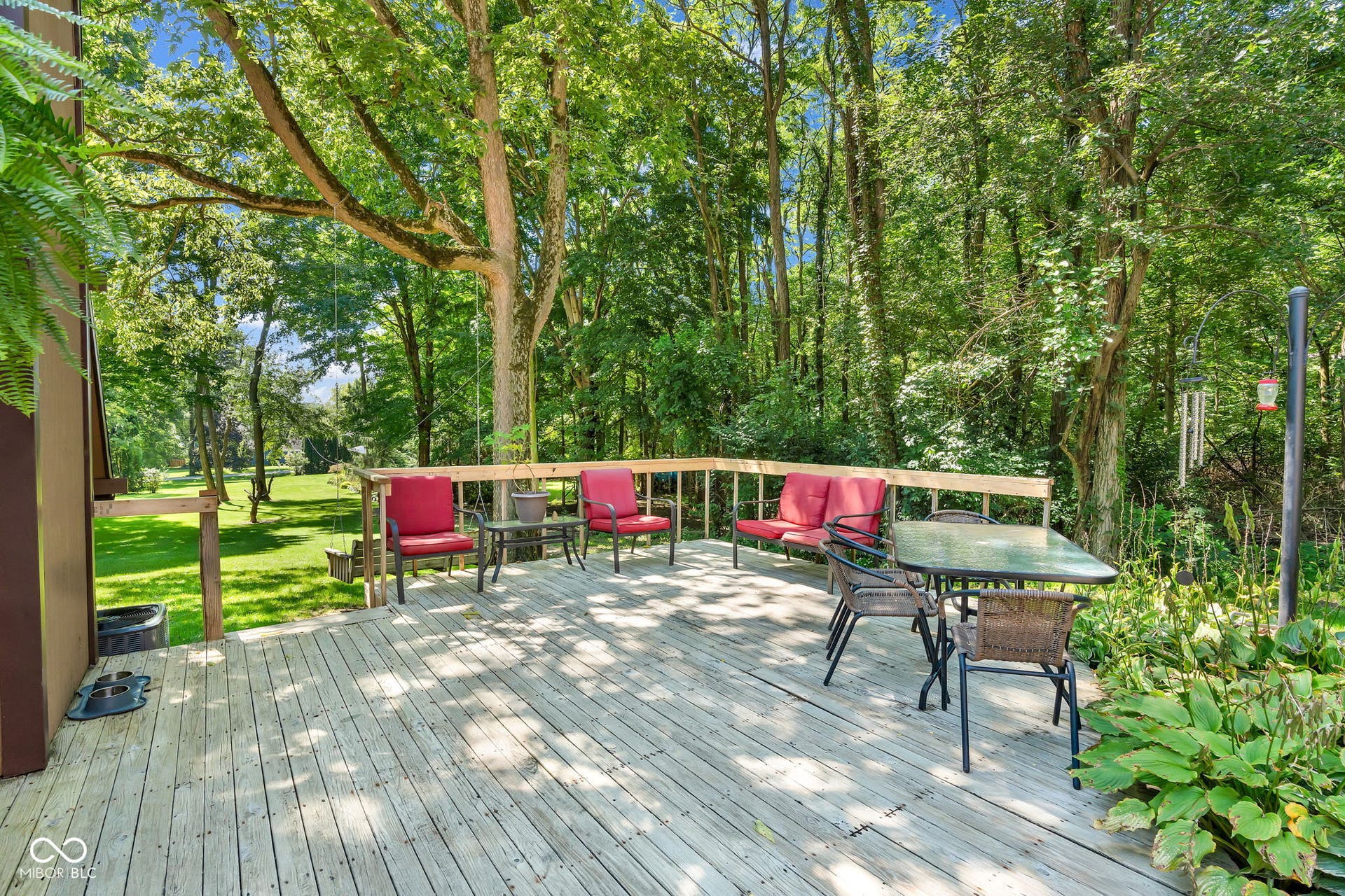 5432 W Whittier Drive, Knightstown, IN 46148 Expansive wood deck with a natural wood railing, surrounded by mature trees and lush greenery