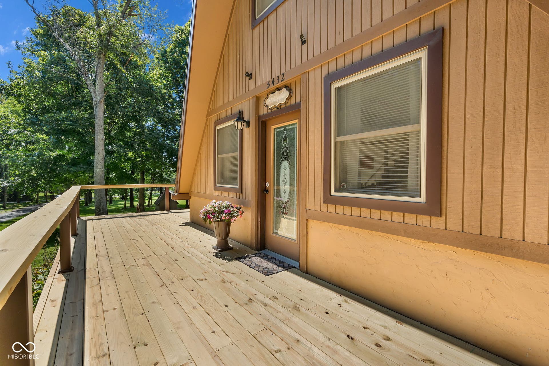 5432 W Whittier Drive, Knightstown, IN 46148 Expansive wood deck with railing, A-frame exterior with vertical siding, decorative glass entry door, and exterior wall lantern