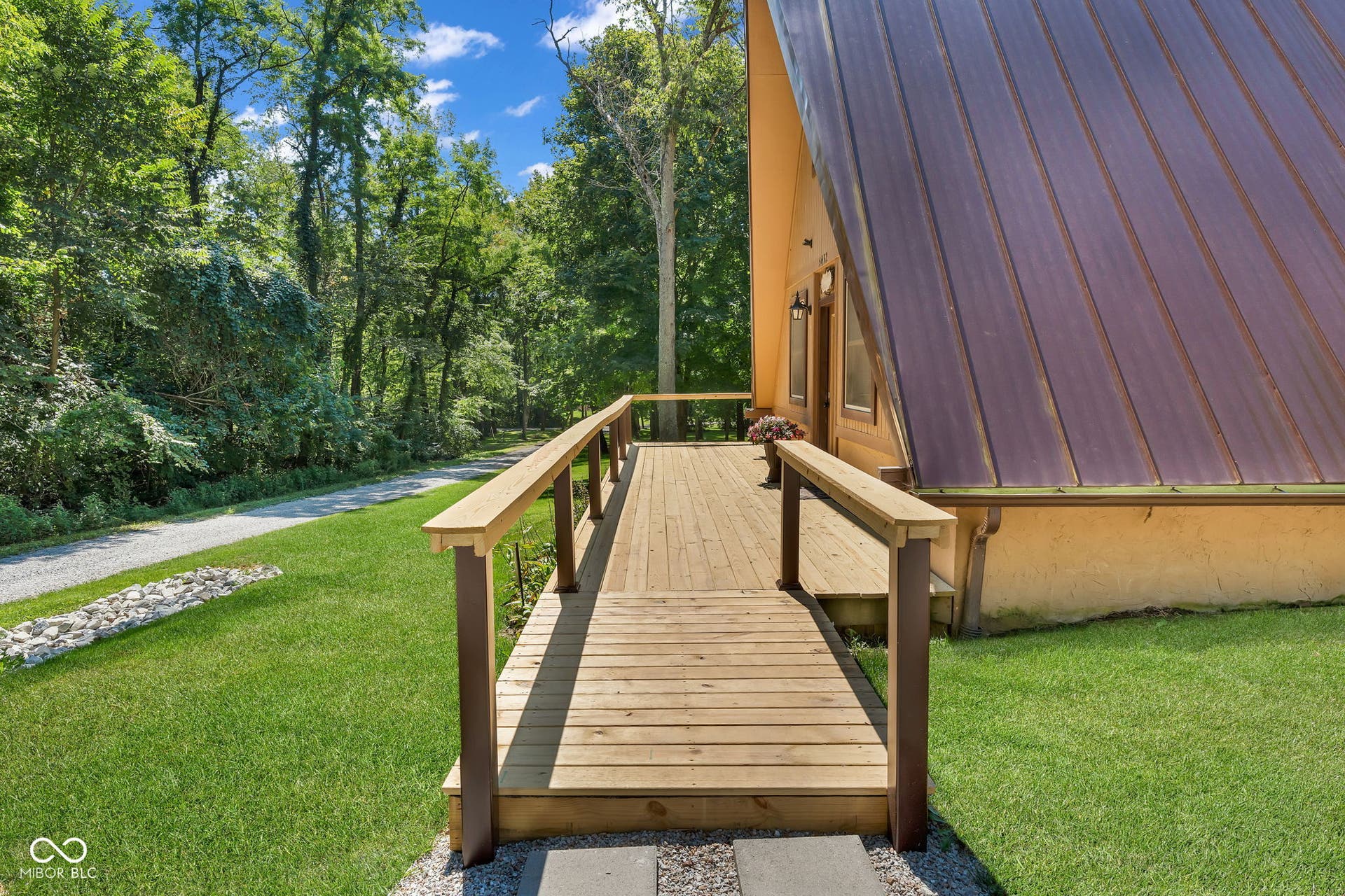 5432 W Whittier Drive, Knightstown, IN 46148 Wood ramp to front door. A-frame architecture featuring a metal roof, wood deck, gravel driveway, and surrounding mature trees