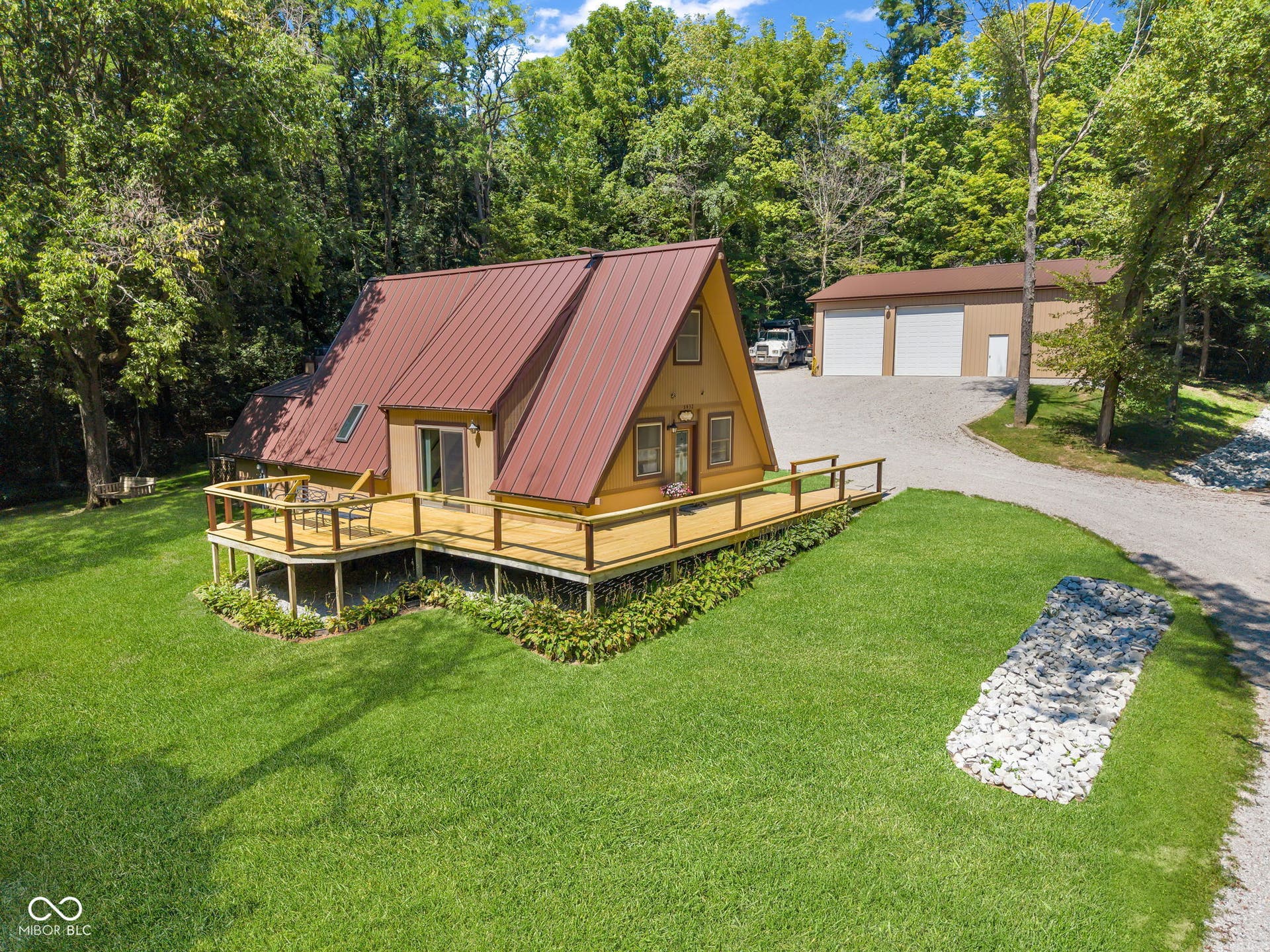 5432 W Whittier Drive, Knightstown, IN 46148 A-frame residence with a red metal roof, expansive wood deck, and a detached pole barn