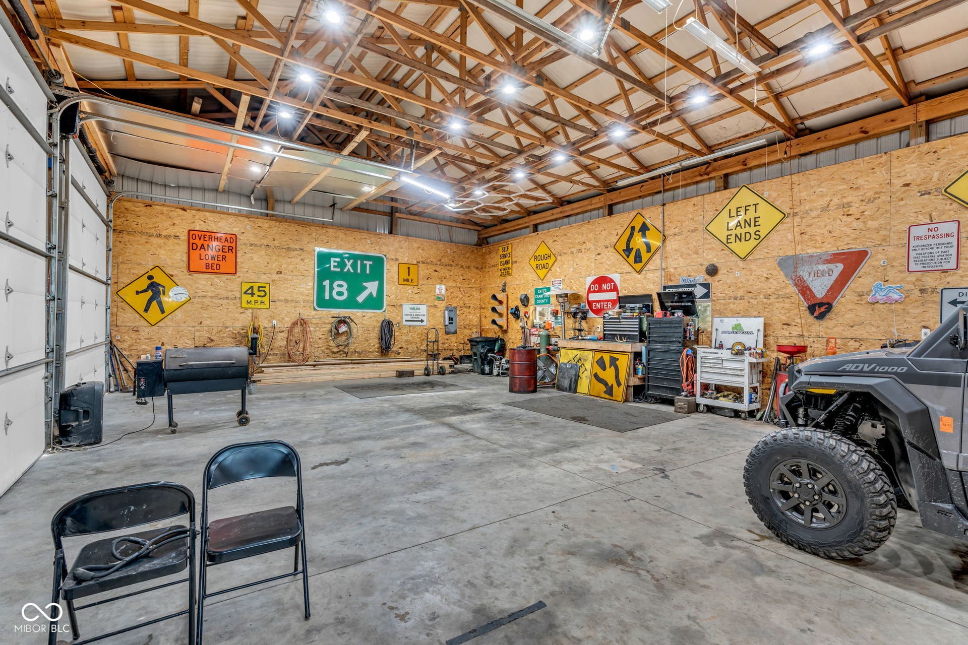 5432 W Whittier Drive, Knightstown, IN 46148 Spacious interior featuring a high exposed beam ceiling, concrete flooring, and roll-up garage doors