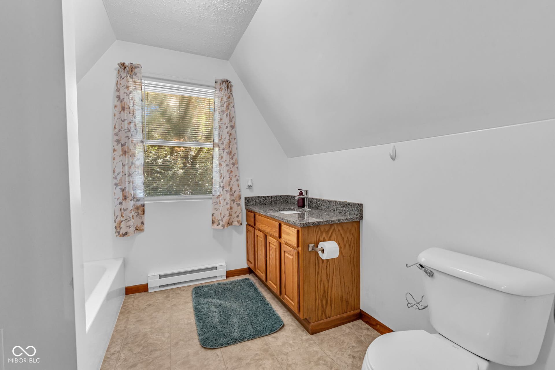 5432 W Whittier Drive, Knightstown, IN 46148 Sloped ceiling bathroom featuring a single window, a built-in wood vanity with a stone-finish countertop, and a white toilet