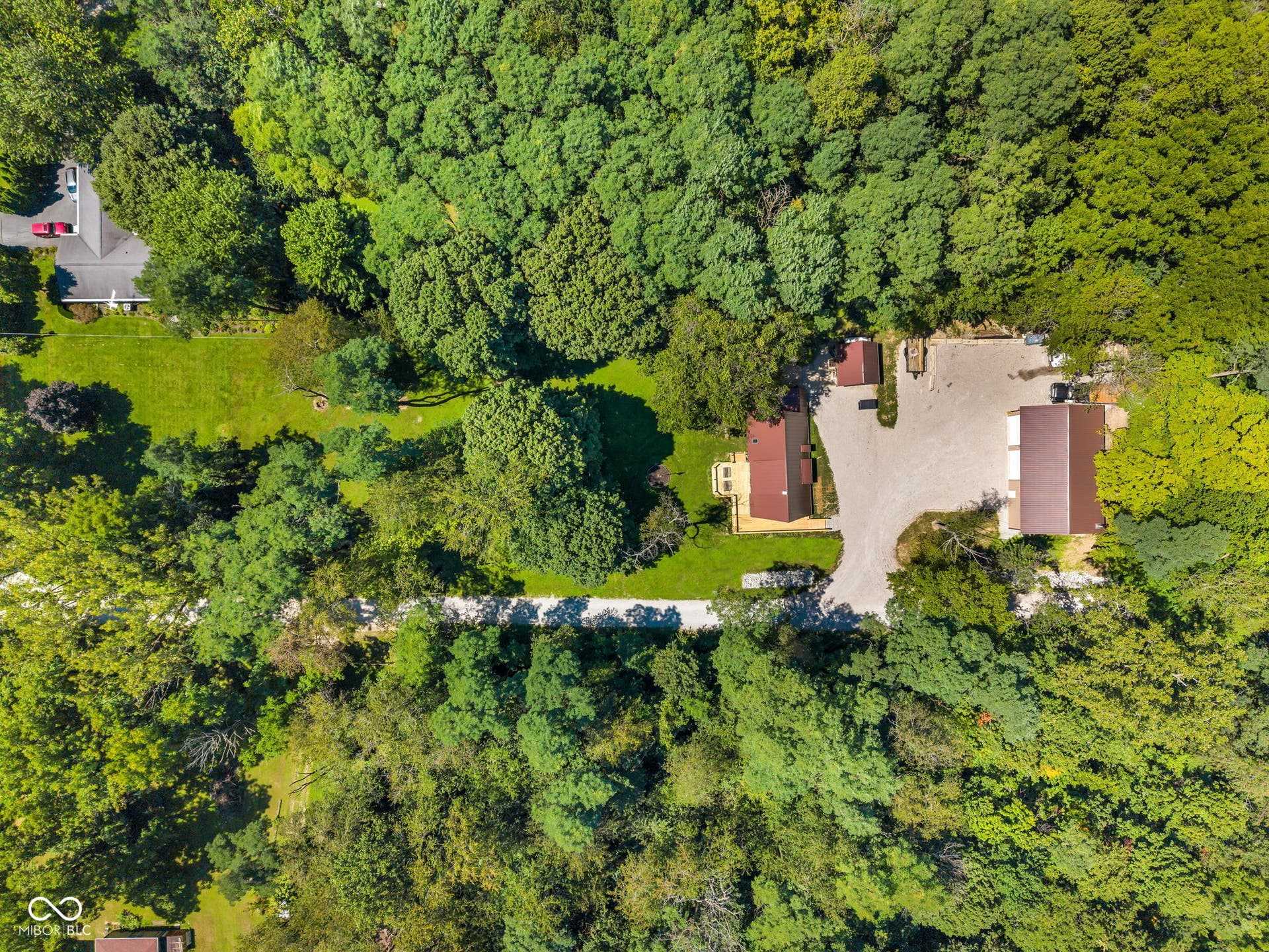 5432 W Whittier Drive, Knightstown, IN 46148 Wooded acreage featuring two separate structures, a gravel driveway, and a manicured lawn