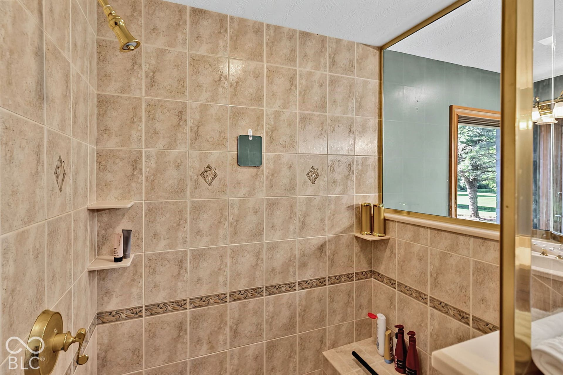 Tiled shower enclosure featuring a built-in bench, corner shelving, and decorative tile accents