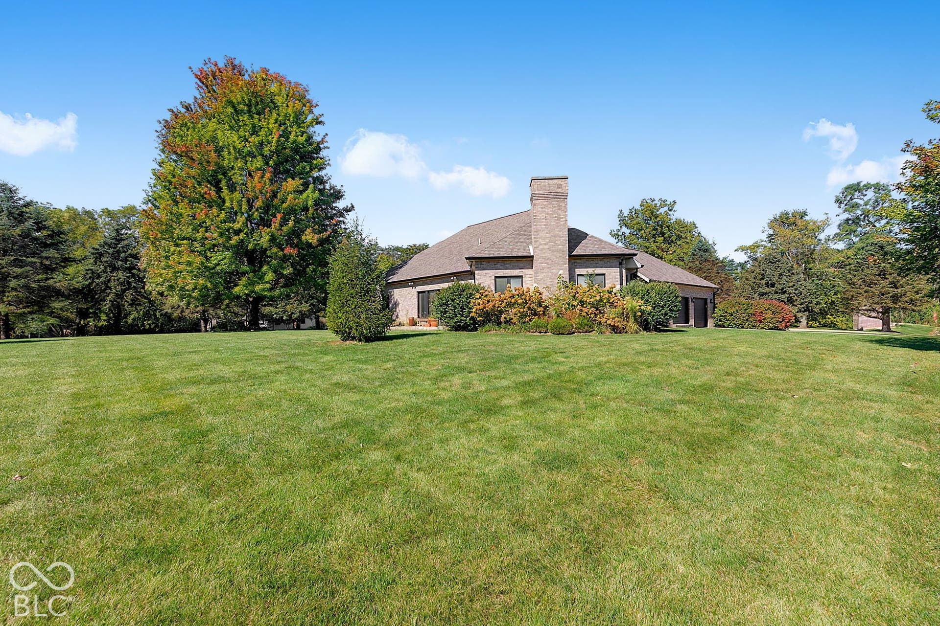 Brick exterior residence featuring a prominent chimney, dark-framed windows, and an attached garage