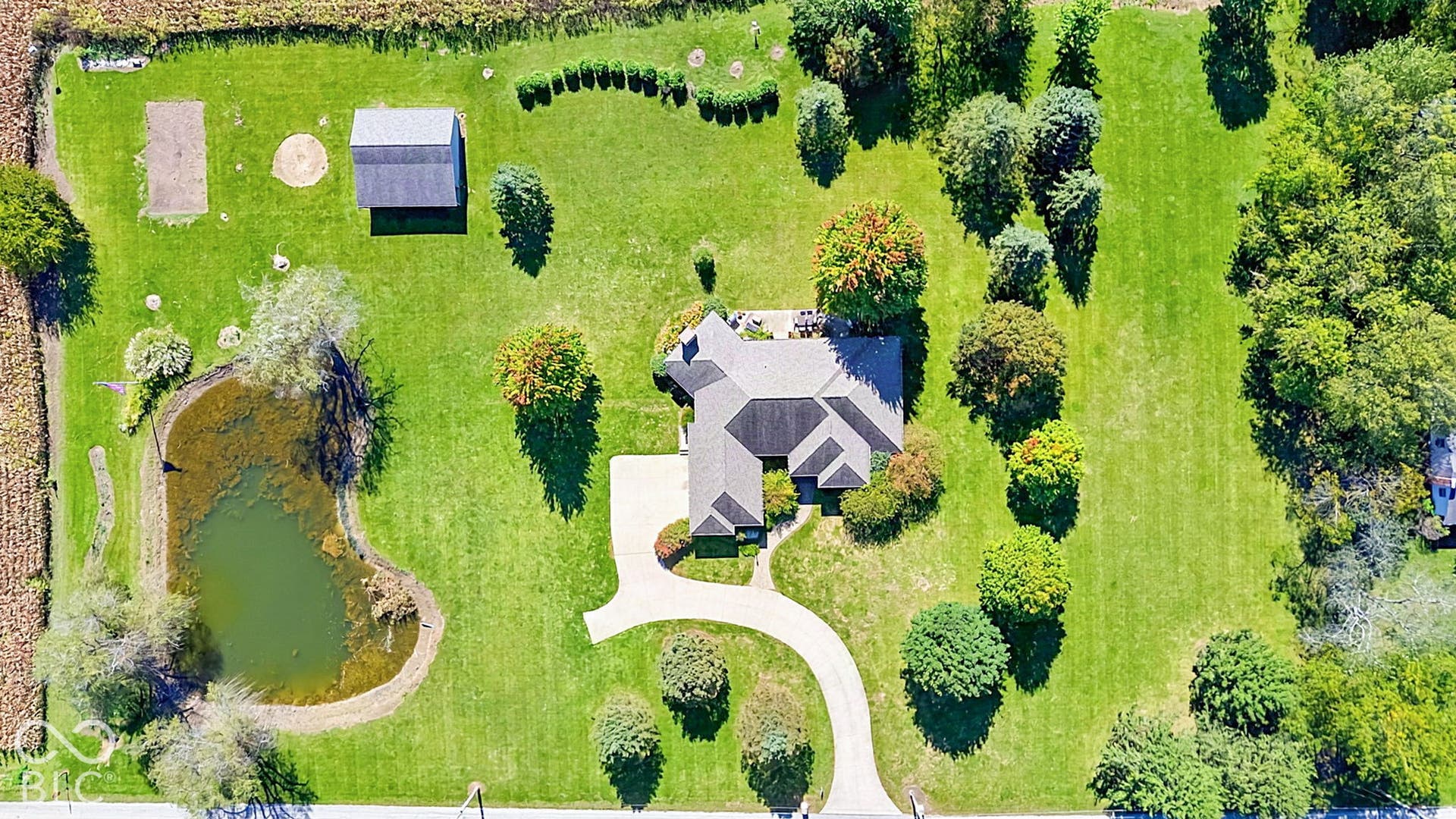 Expansive lot featuring a large pond, detached outbuilding, extensive lawn, and mature trees