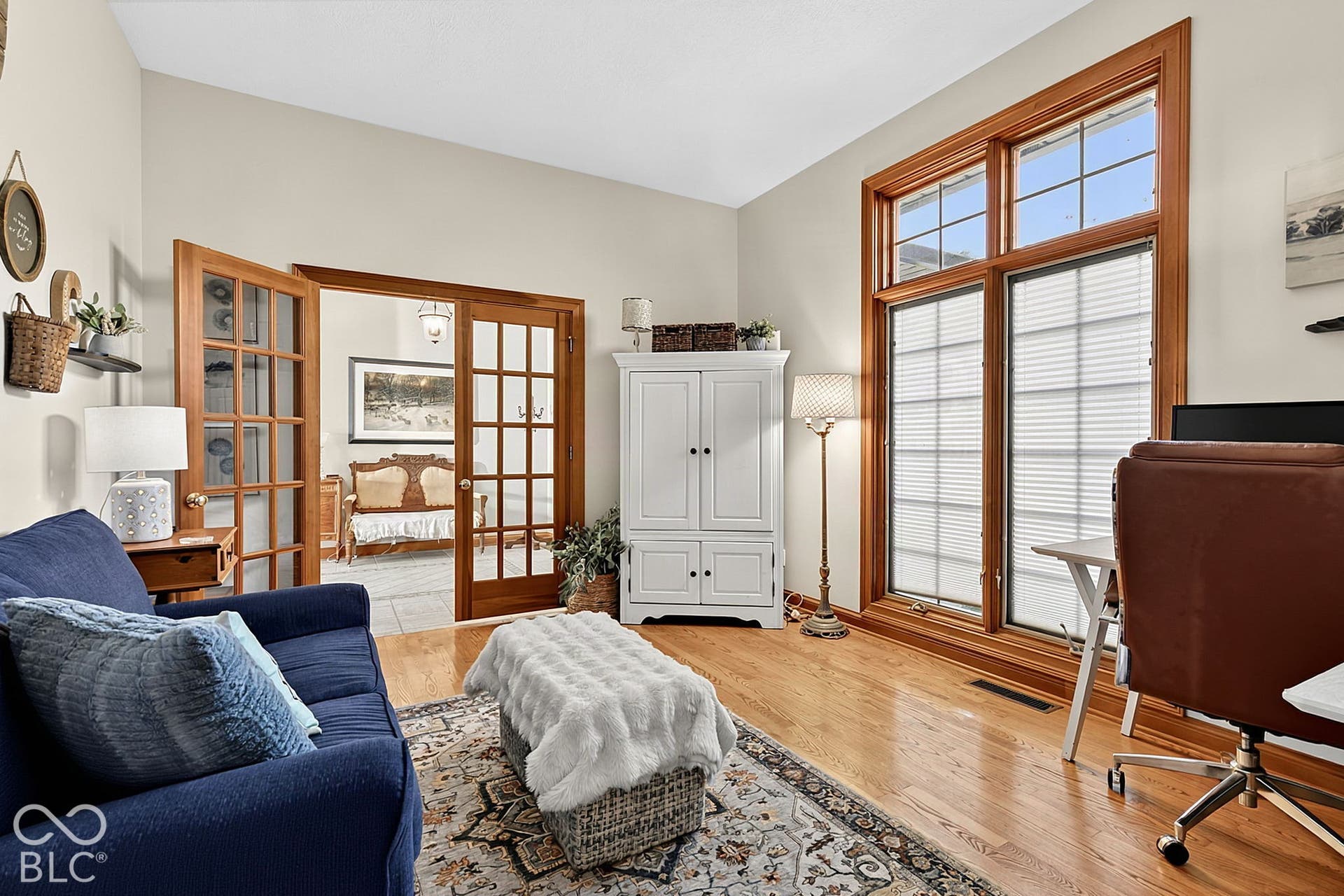 Hardwood flooring, soaring vaulted ceiling, French doors, and a large multi-pane window with wood trim