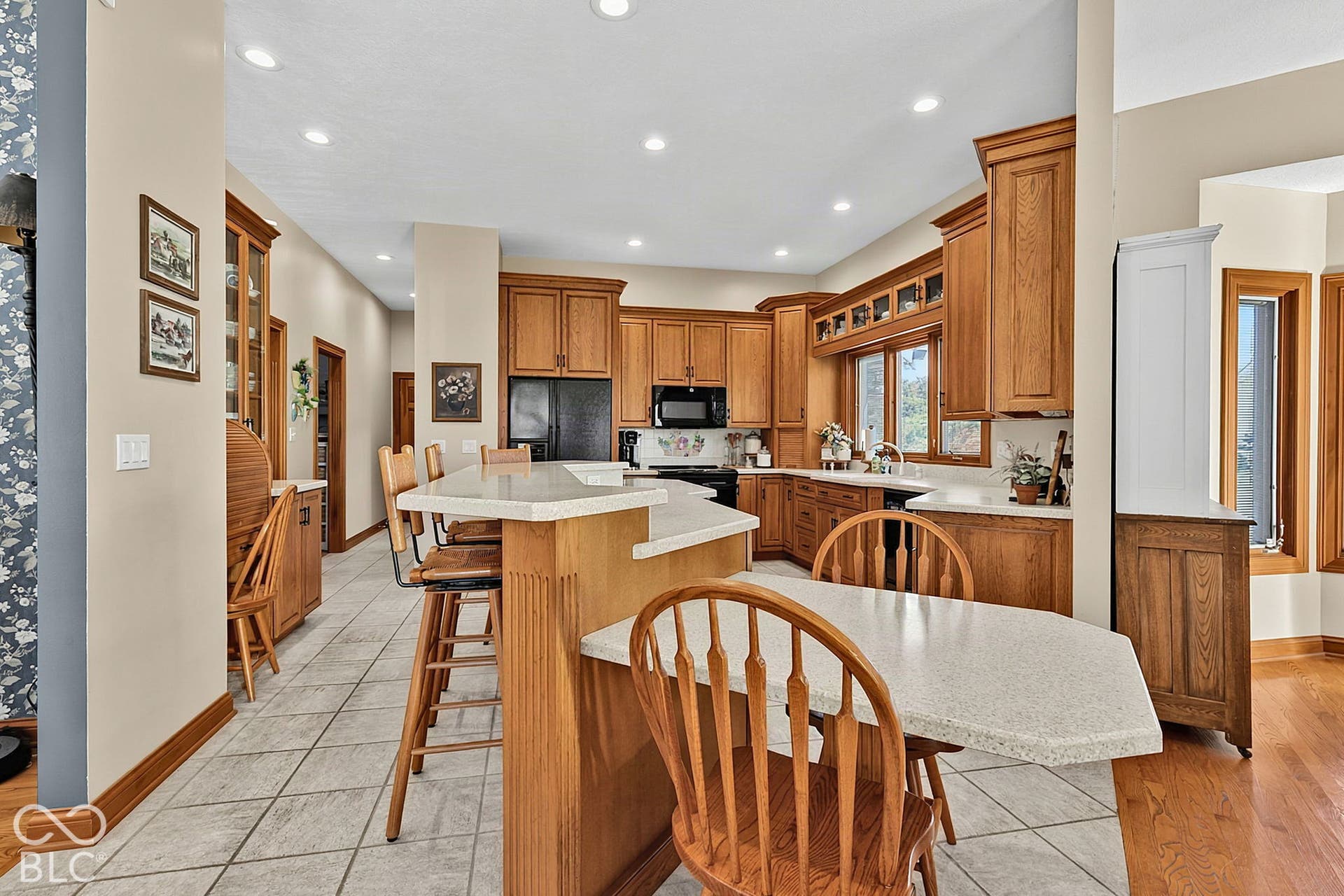 Kitchen featuring wood cabinetry, an island with countertop seating, recessed lighting, and tile flooring