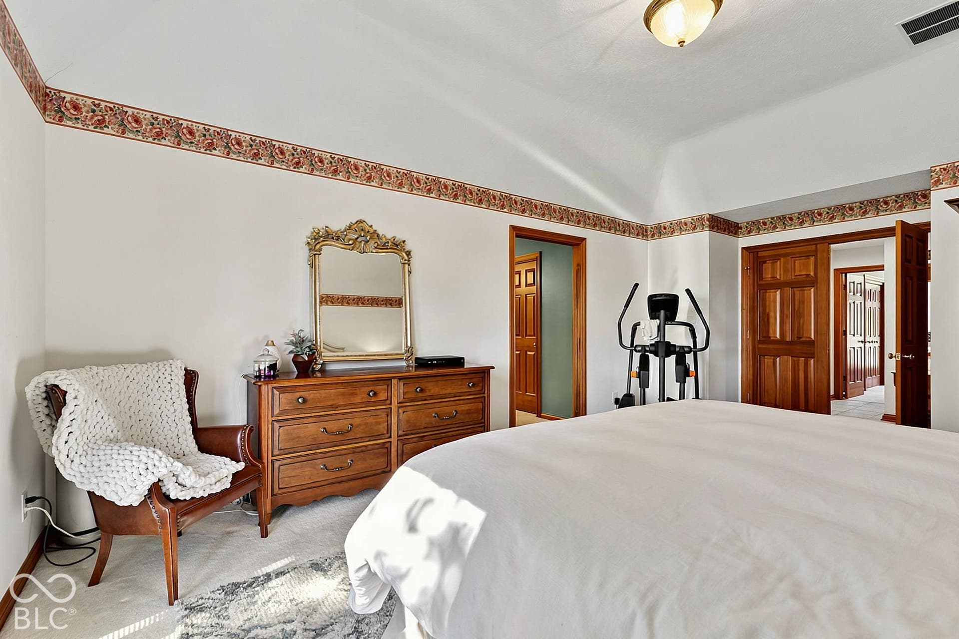 Vaulted ceiling with decorative trim, wood-finish doors, and flush-mount lighting