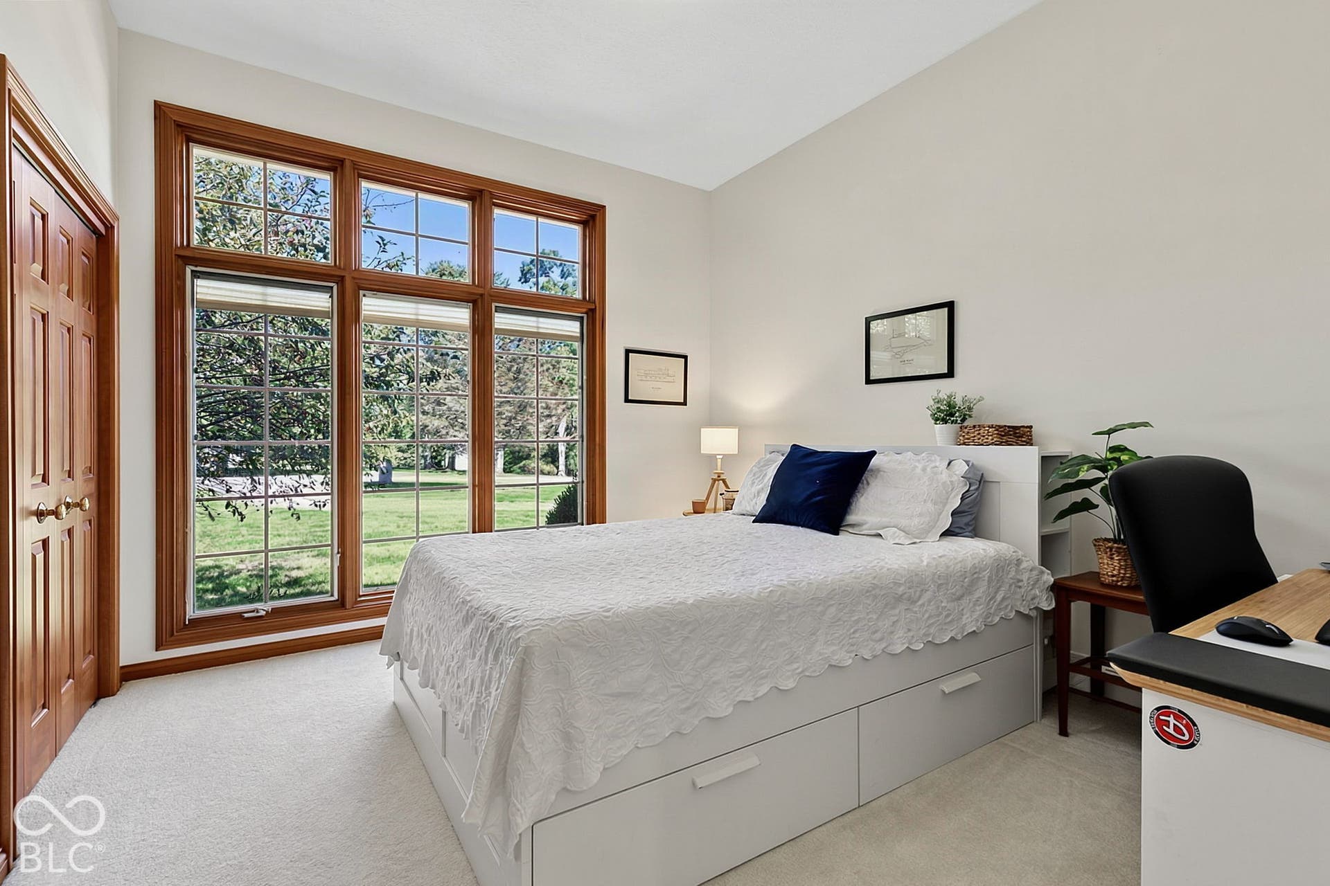 Expansive window featuring wood trim, neutral wall color, and light-colored carpeting
