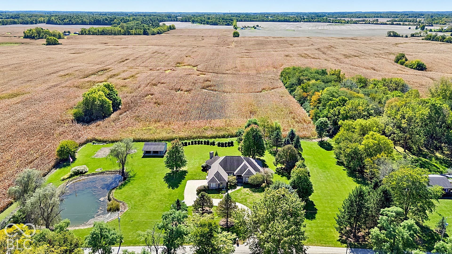 Expansive property featuring a large residence with a multi-gabled roof, a private pond, and extensive manicured lawns