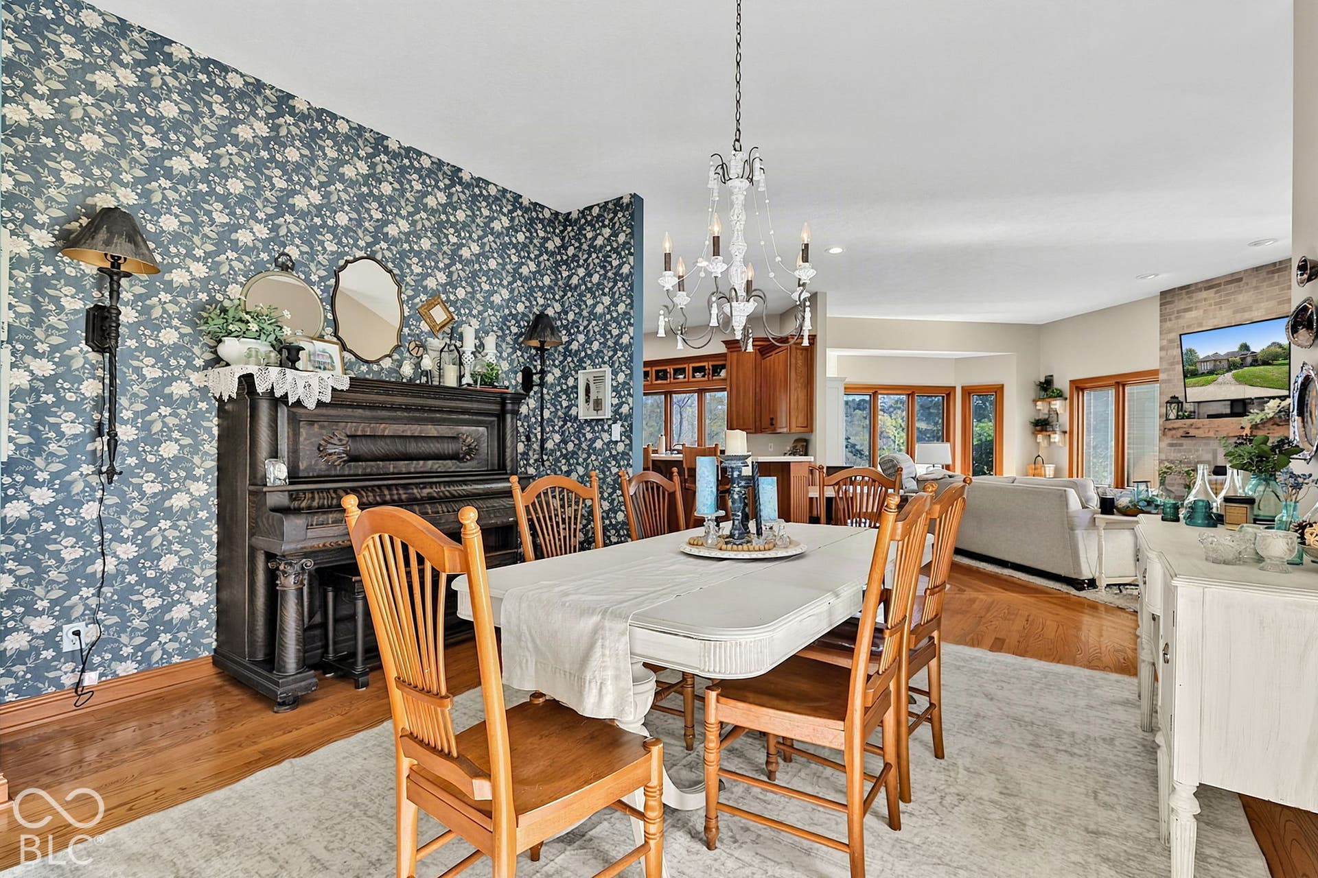 Open-concept dining area with wood-finish flooring, a chandelier, and a decorative accent wall