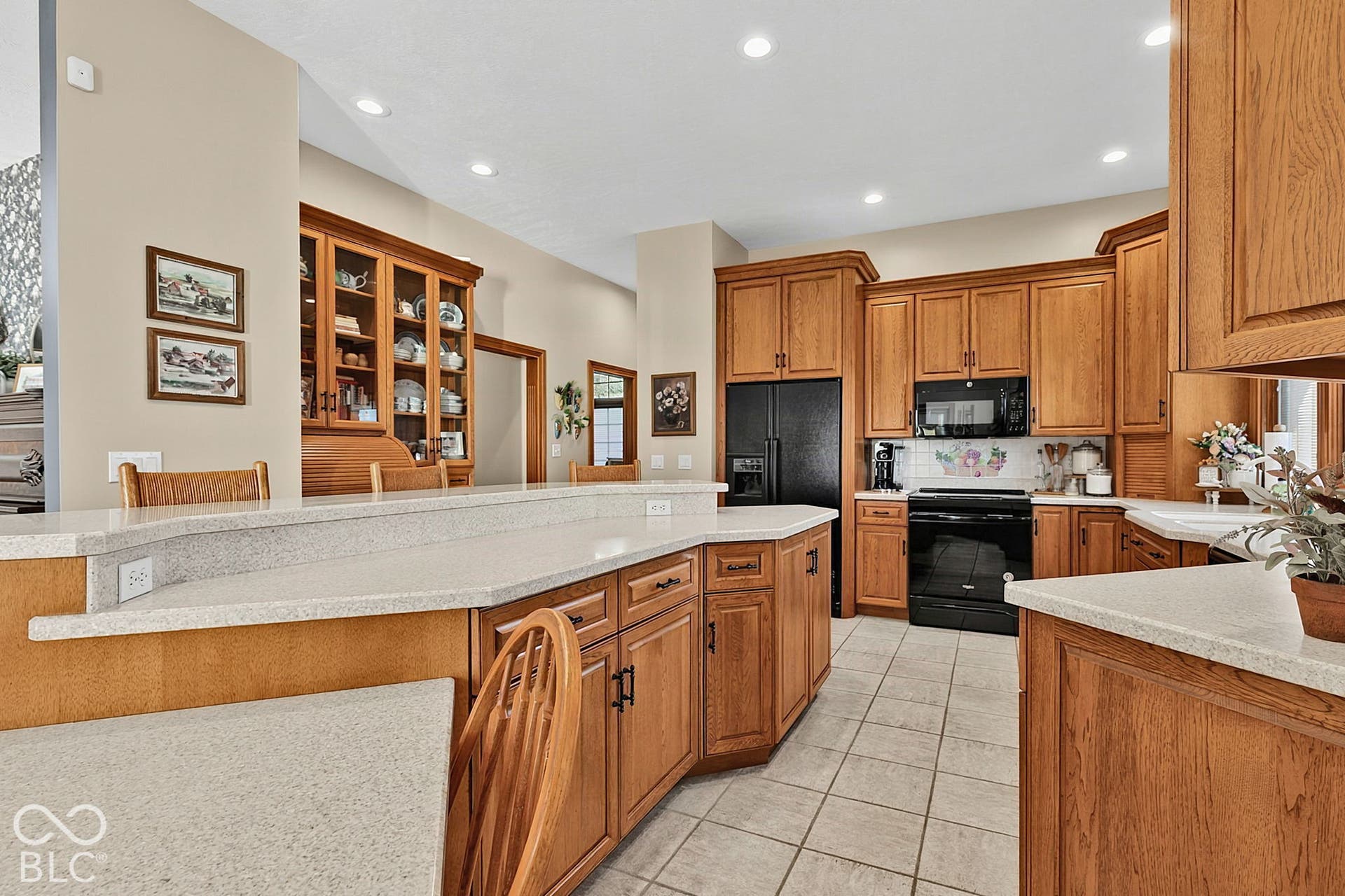 Kitchen featuring light wood cabinetry, light-toned countertops, black appliances, recessed lighting, and tile flooring