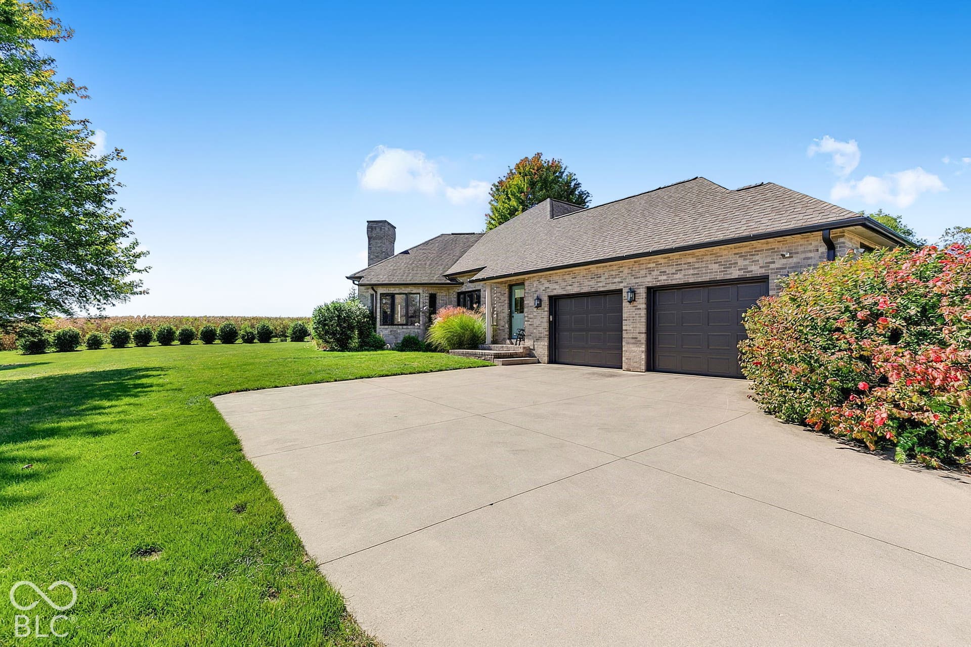 Brick exterior with a stone chimney, two-car garage, and concrete driveway