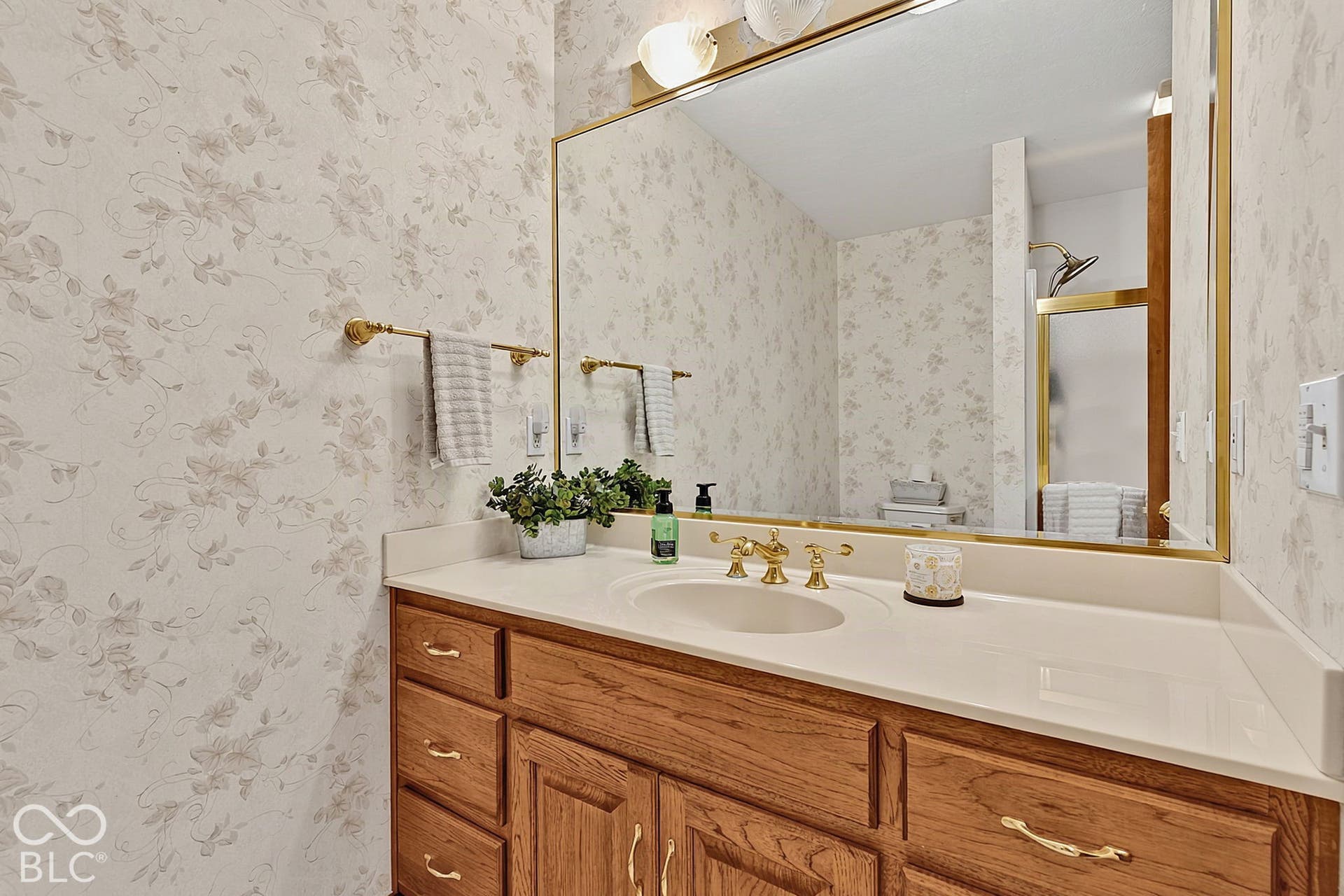 Custom vanity with integrated sink, gold-finish faucet, and coordinating gold-framed mirror