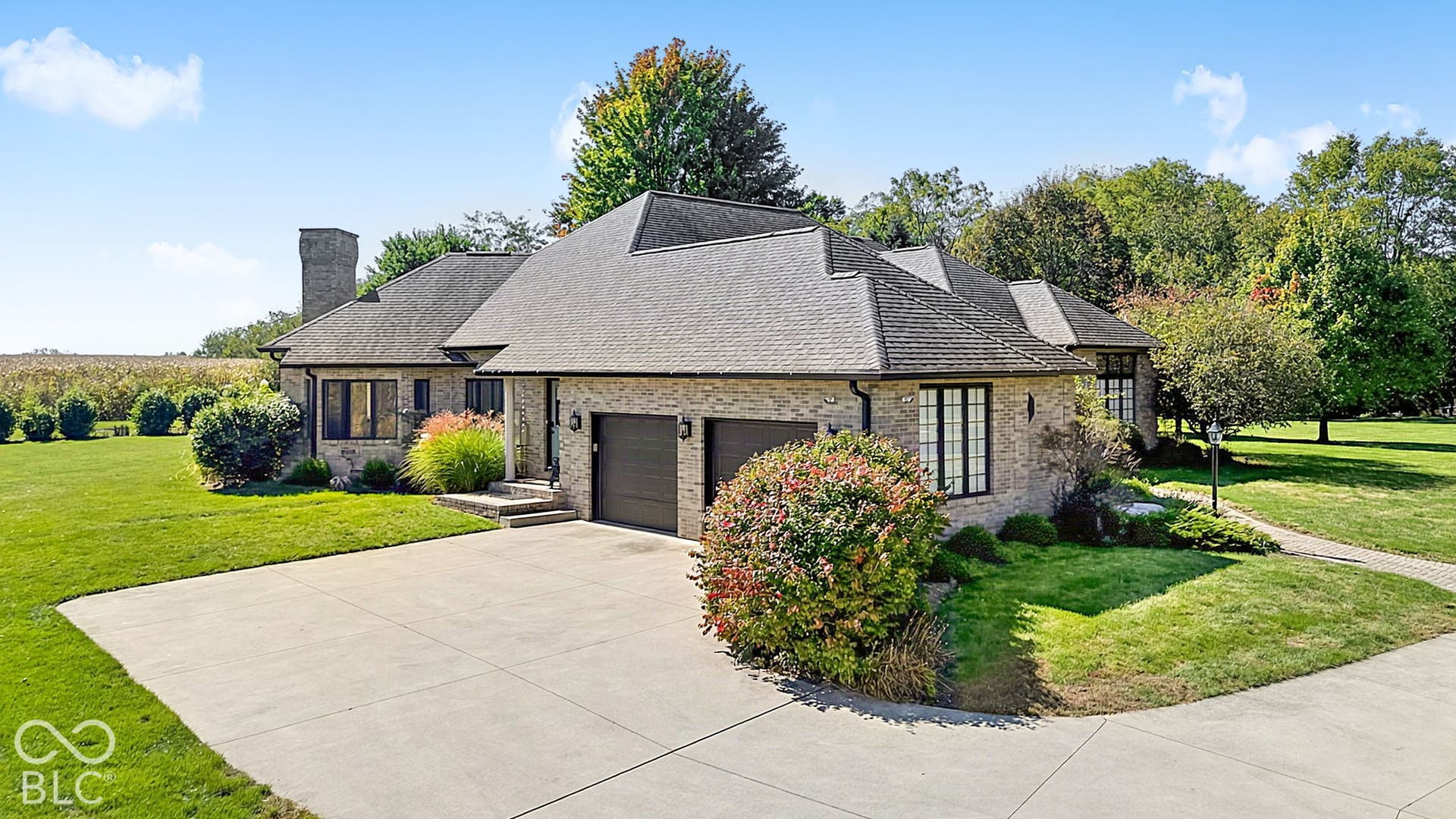 Brick exterior with dark-framed windows, an attached two-car garage, a concrete driveway, and a shingle roof