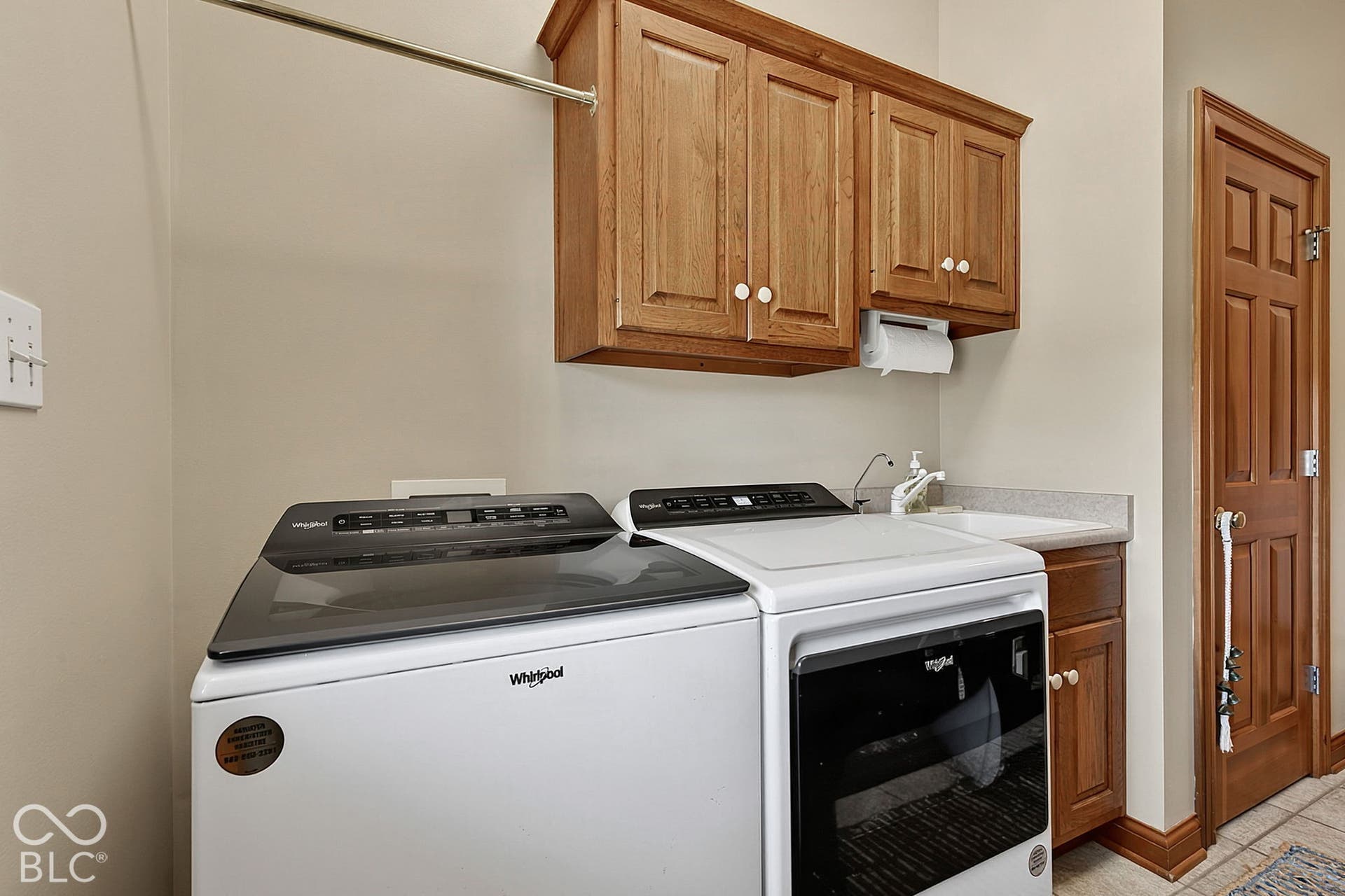 Laundry area featuring upper wood-finish cabinetry, a built-in sink, and a countertop