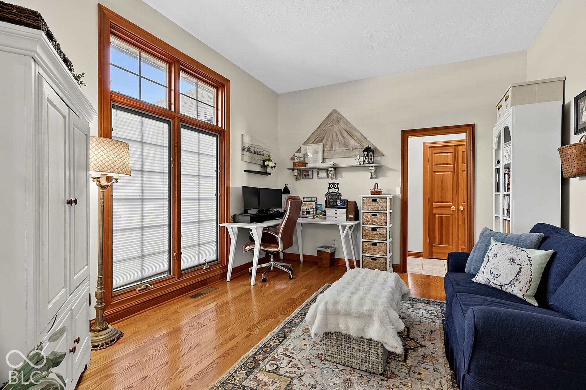 Hardwood flooring, wood-framed windows, and a built-in white storage cabinet