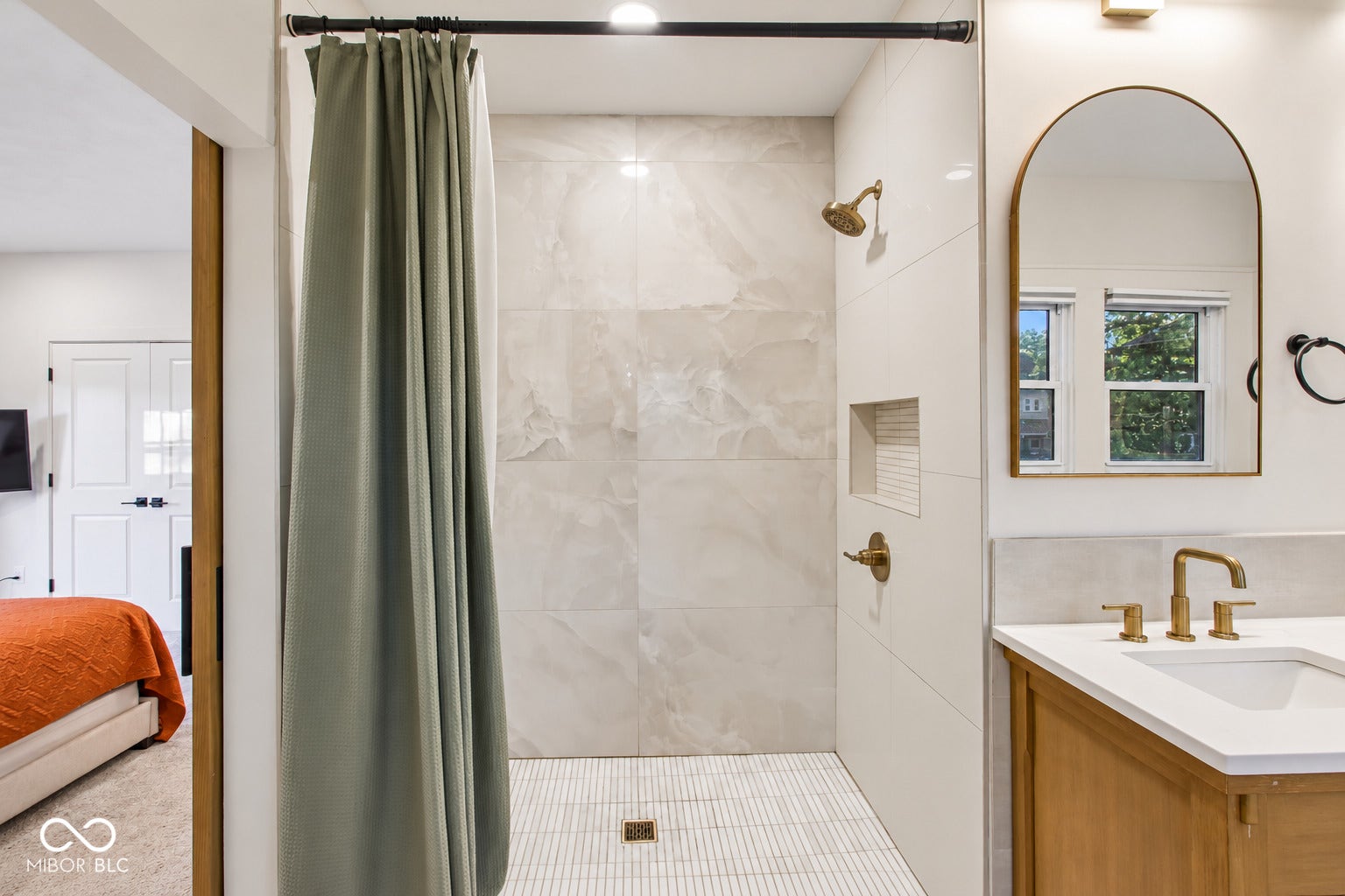 Tiled shower with a built-in niche and brass-finish fixtures