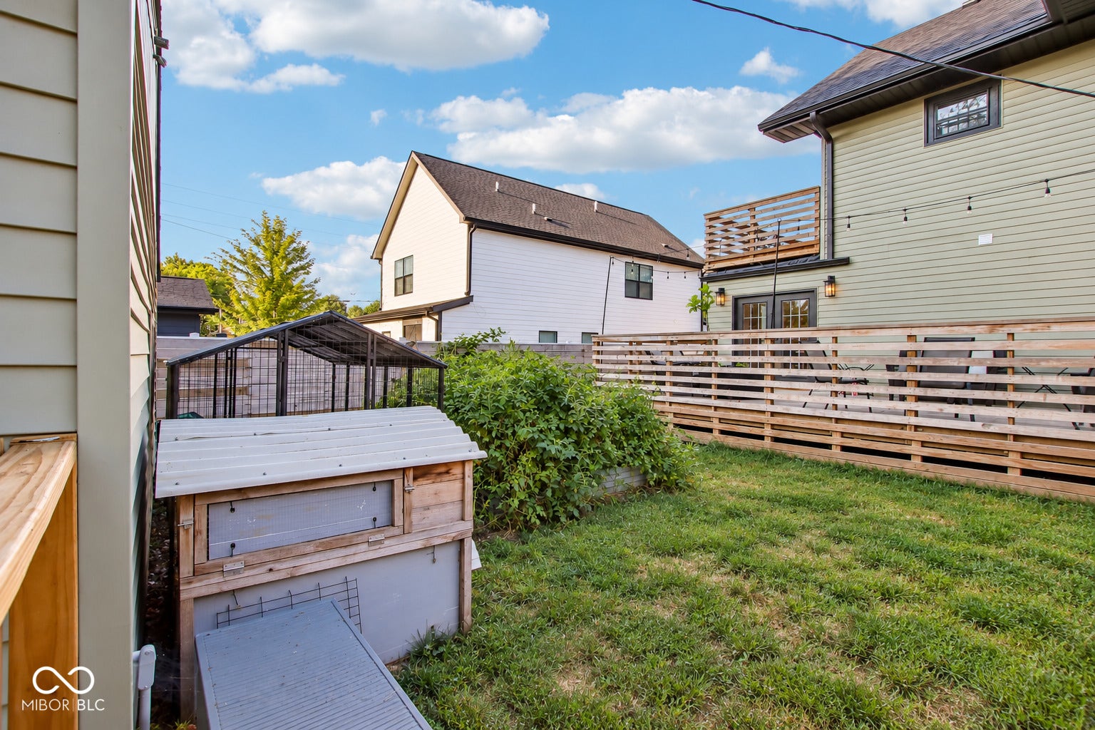 Expansive backyard featuring a manicured lawn, a raised garden bed, and a wooden privacy fence, and a chicken coop
