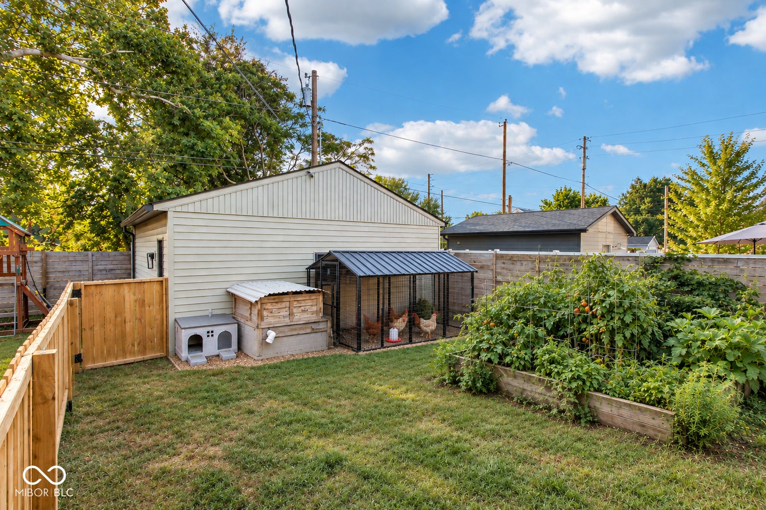 Expansive backyard featuring a manicured lawn, a raised garden bed, and a wooden privacy fence, and a chicken coop