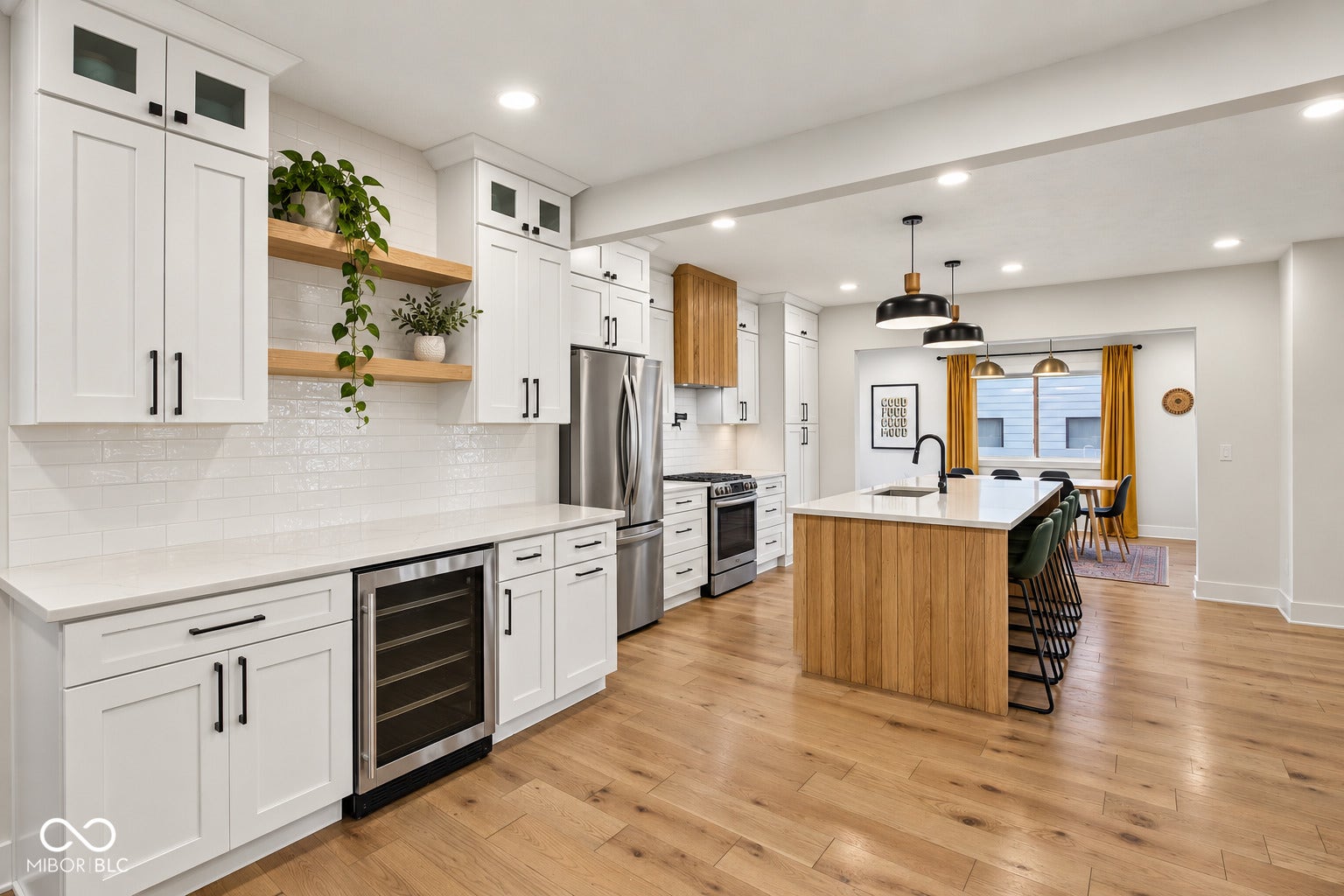Contemporary kitchen featuring white cabinetry, a built-in wine cooler, stainless steel appliances, a center island with a sink, and wood-finish flooring