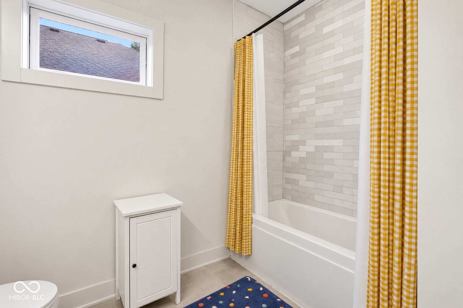 Bathtub with subway tile surround, a window, and light-toned walls