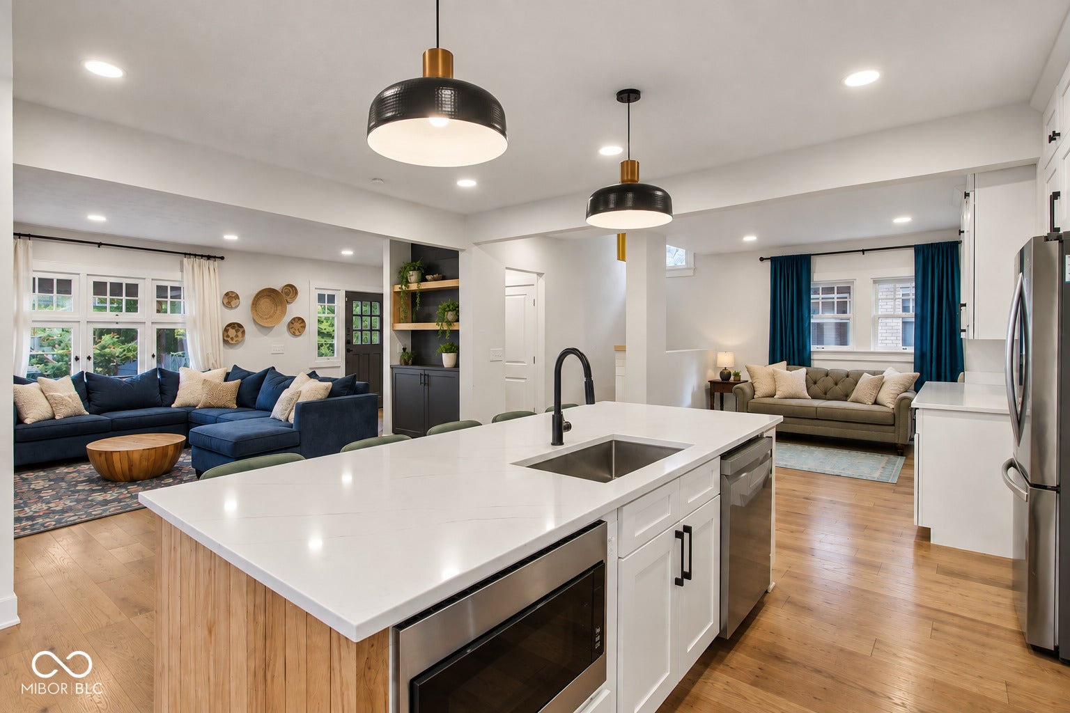 Kitchen island featuring a stainless steel sink, black faucet, integrated microwave, and white quartz countertop