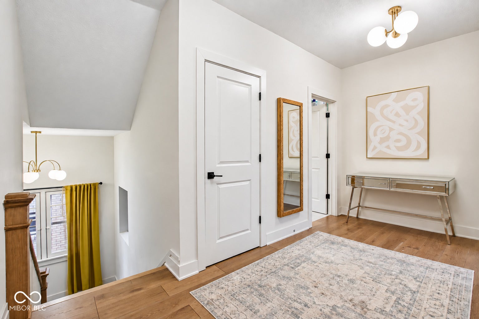 Wood-finish flooring throughout, white paneled doors with matte black hardware, and a modern globe chandelier