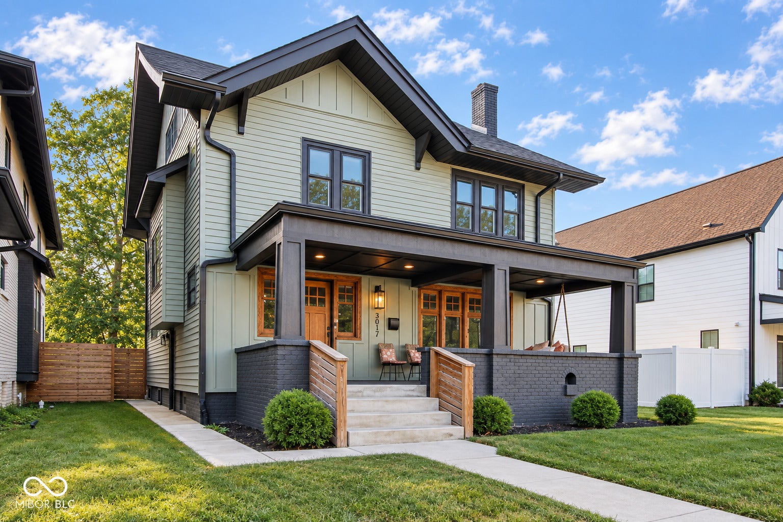 Gable roofline, light green siding, dark trim, covered front porch, and concrete walkway