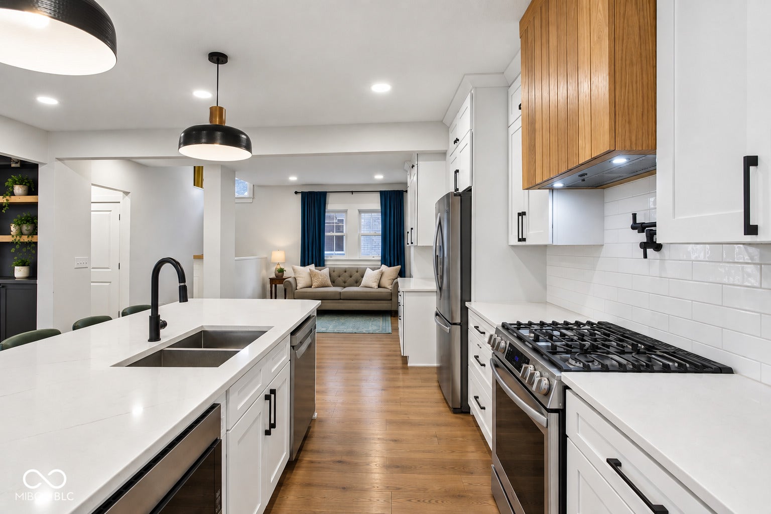 Kitchen featuring white cabinetry, light countertops, wood-finish flooring, stainless steel appliances, and a wood-paneled range hood