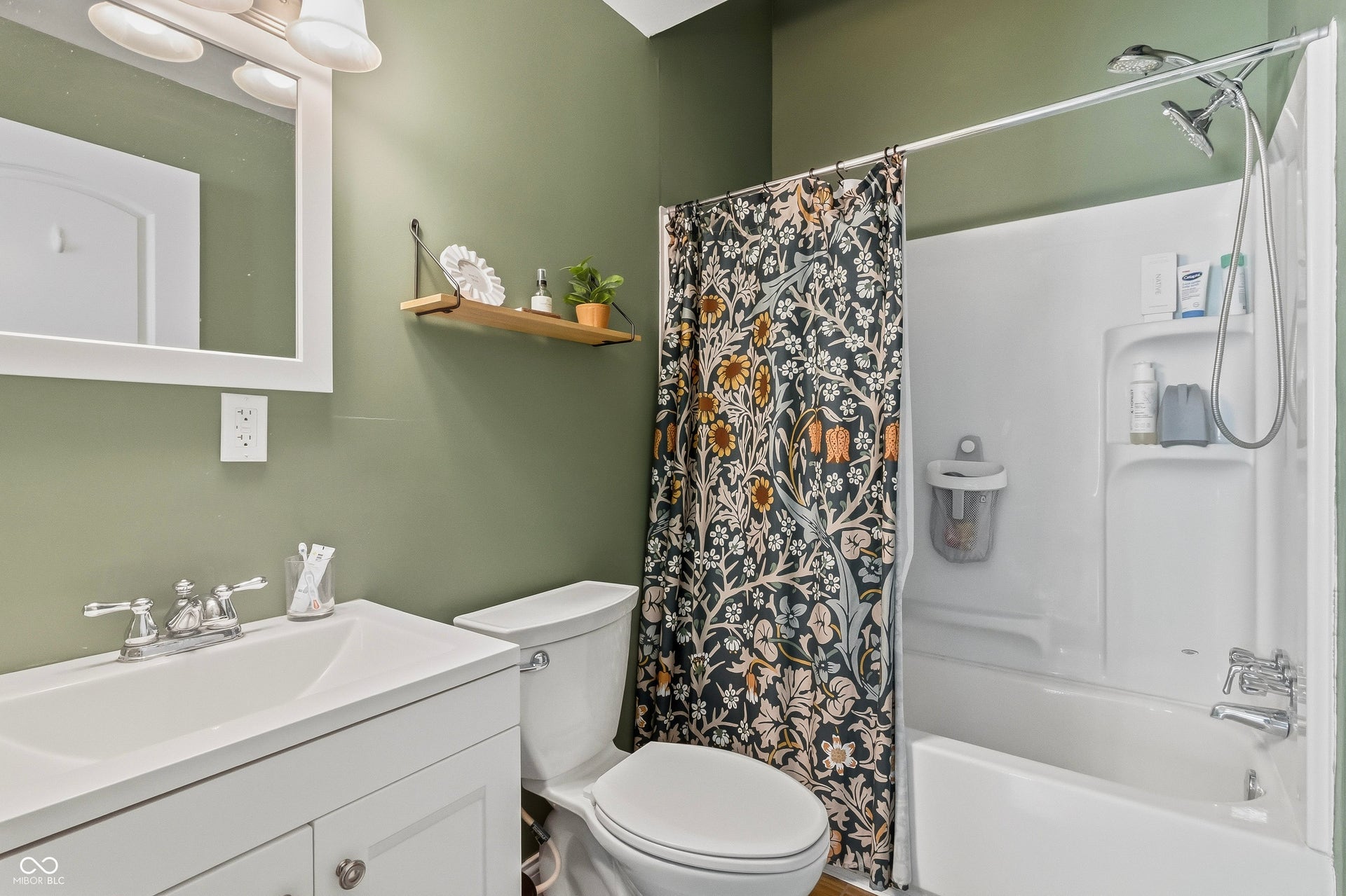 White vanity with integrated sink, chrome faucet, wall-mounted mirror, and overhead lighting