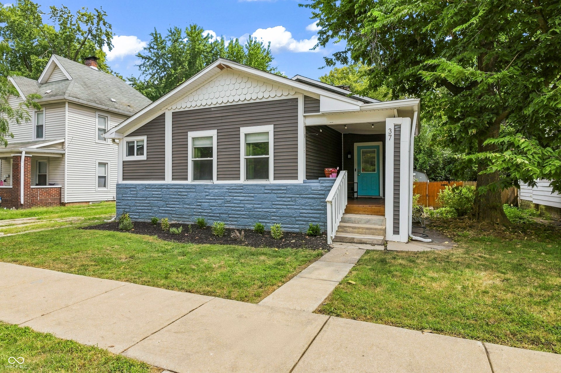 Decorative shingle accents, stone veneer foundation, and a covered entry porch