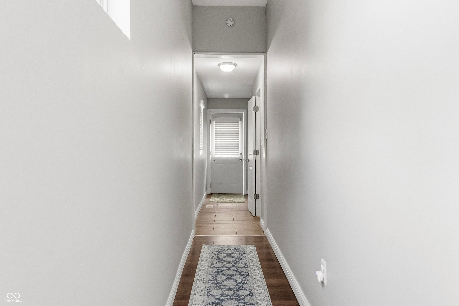 Hallway toward rear entry door, additional half bath, and laundry area