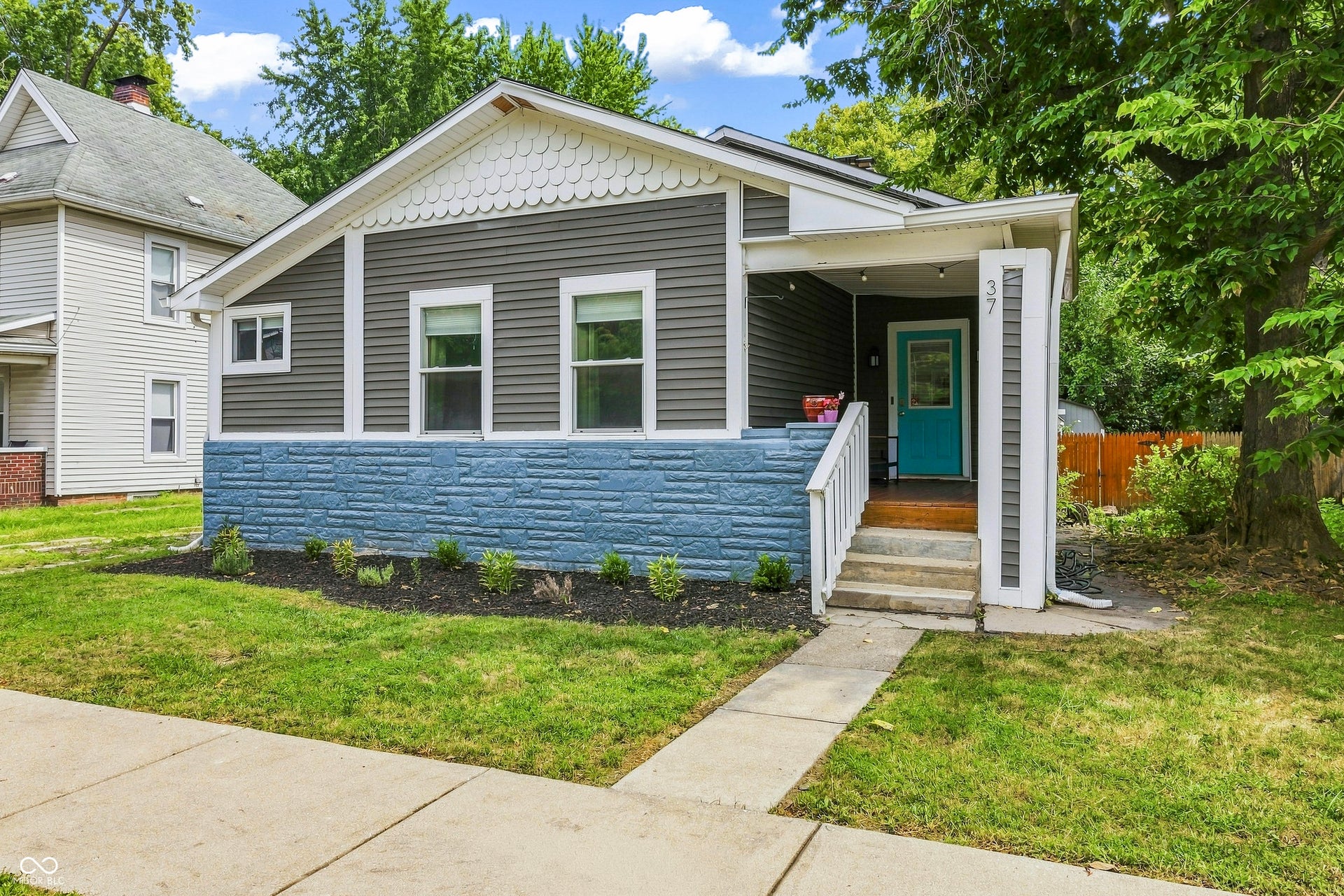 Front exterior with horizontal siding, white trim, and a prominent front porch with a teal entry door