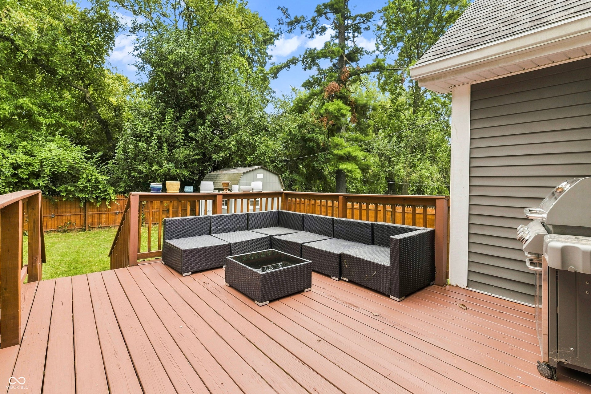 Spacious wood deck in back yard with railing